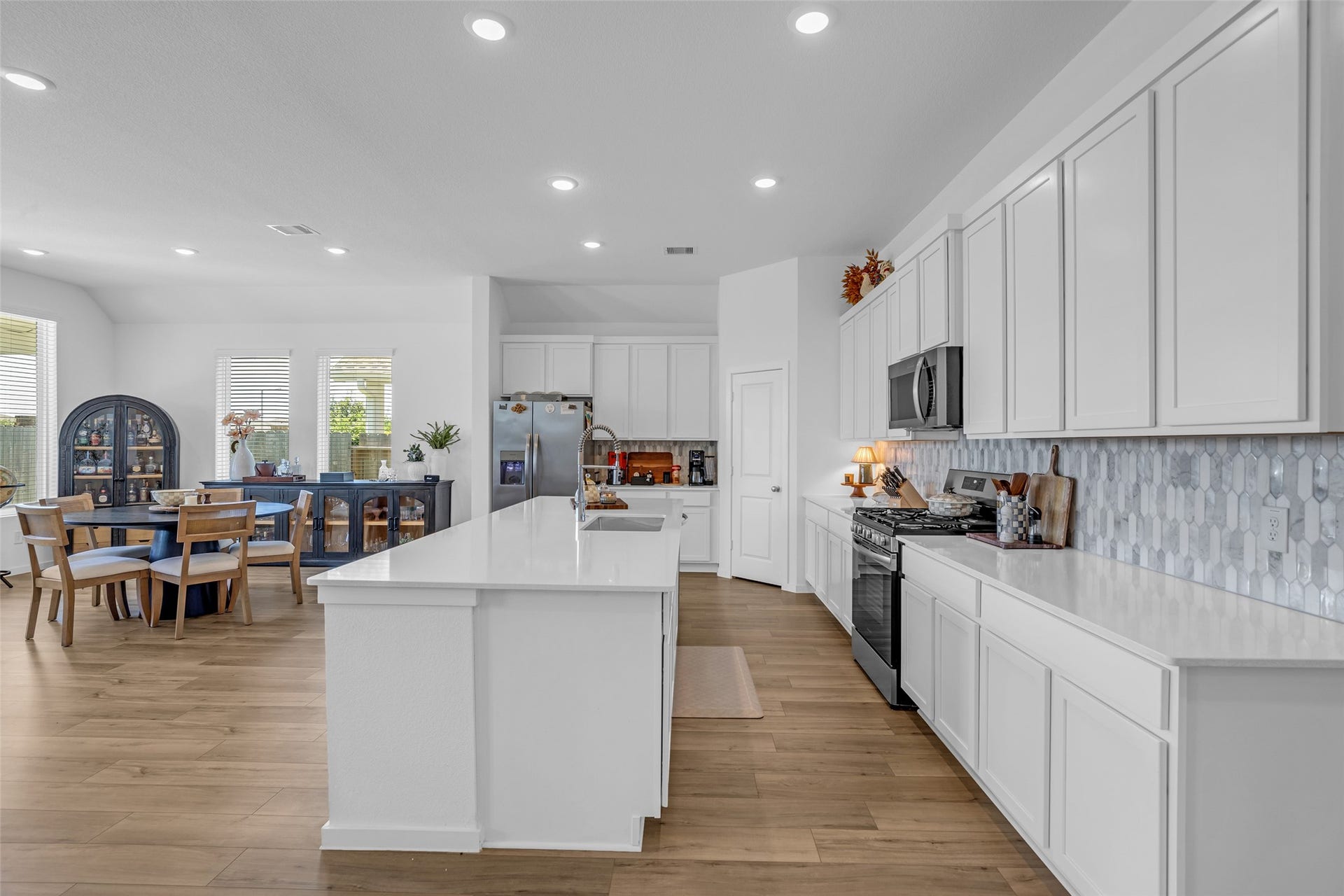 13213 Harbor Point Drive, Texas City, TX 77539 Experience modern living in this open-concept kitchen and dining area, featuring sleek white cabinetry, stainless steel appliances, and a spacious island perfect for entertaining. The adjacent dining space offers ample natural light and a cozy atmosphere.