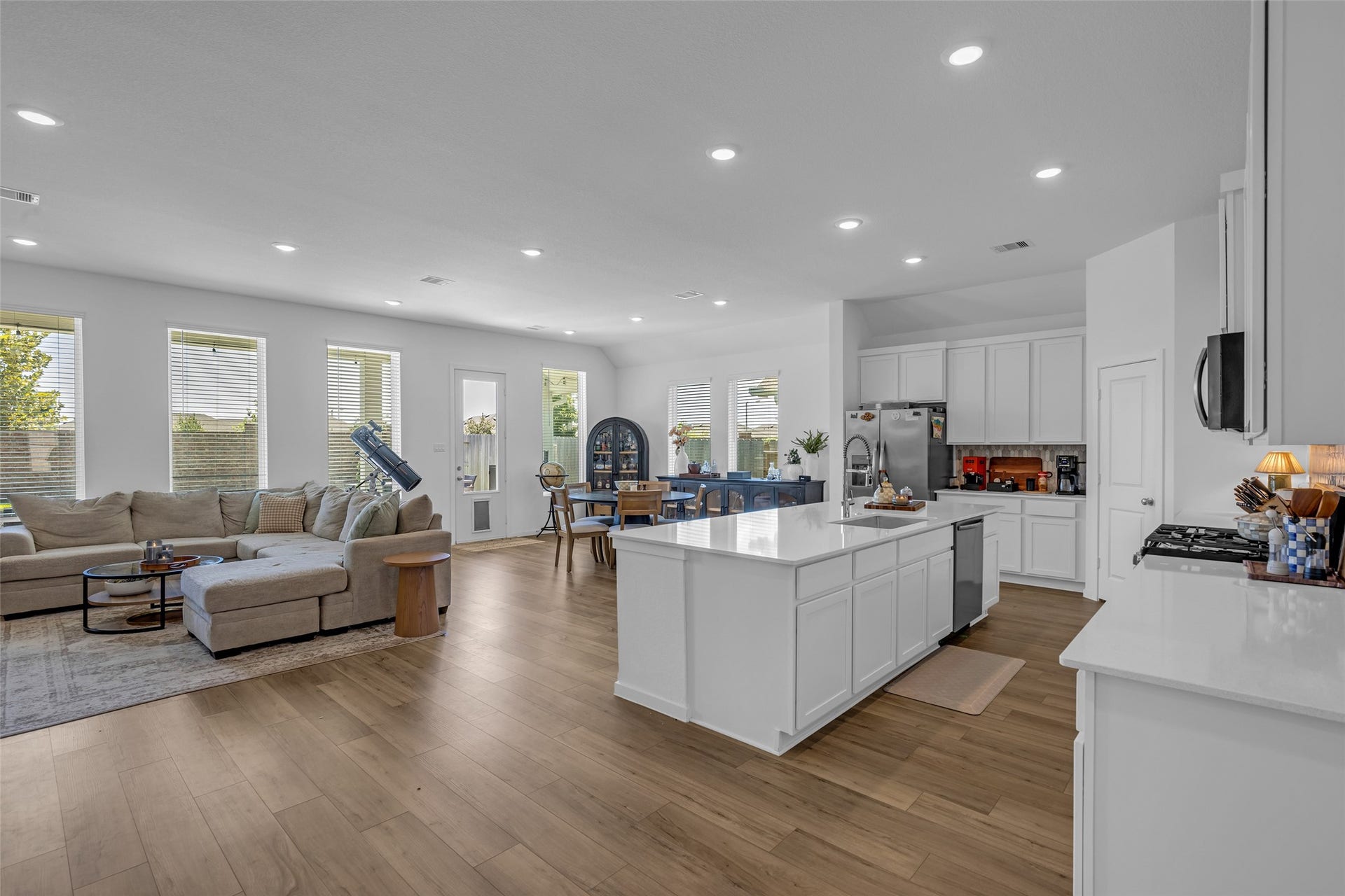 13213 Harbor Point Drive, Texas City, TX 77539 Spacious open-concept living area with abundant natural light, featuring a modern kitchen with a large island, sleek cabinetry, and stainless steel appliances, seamlessly flowing into a cozy living and dining space.