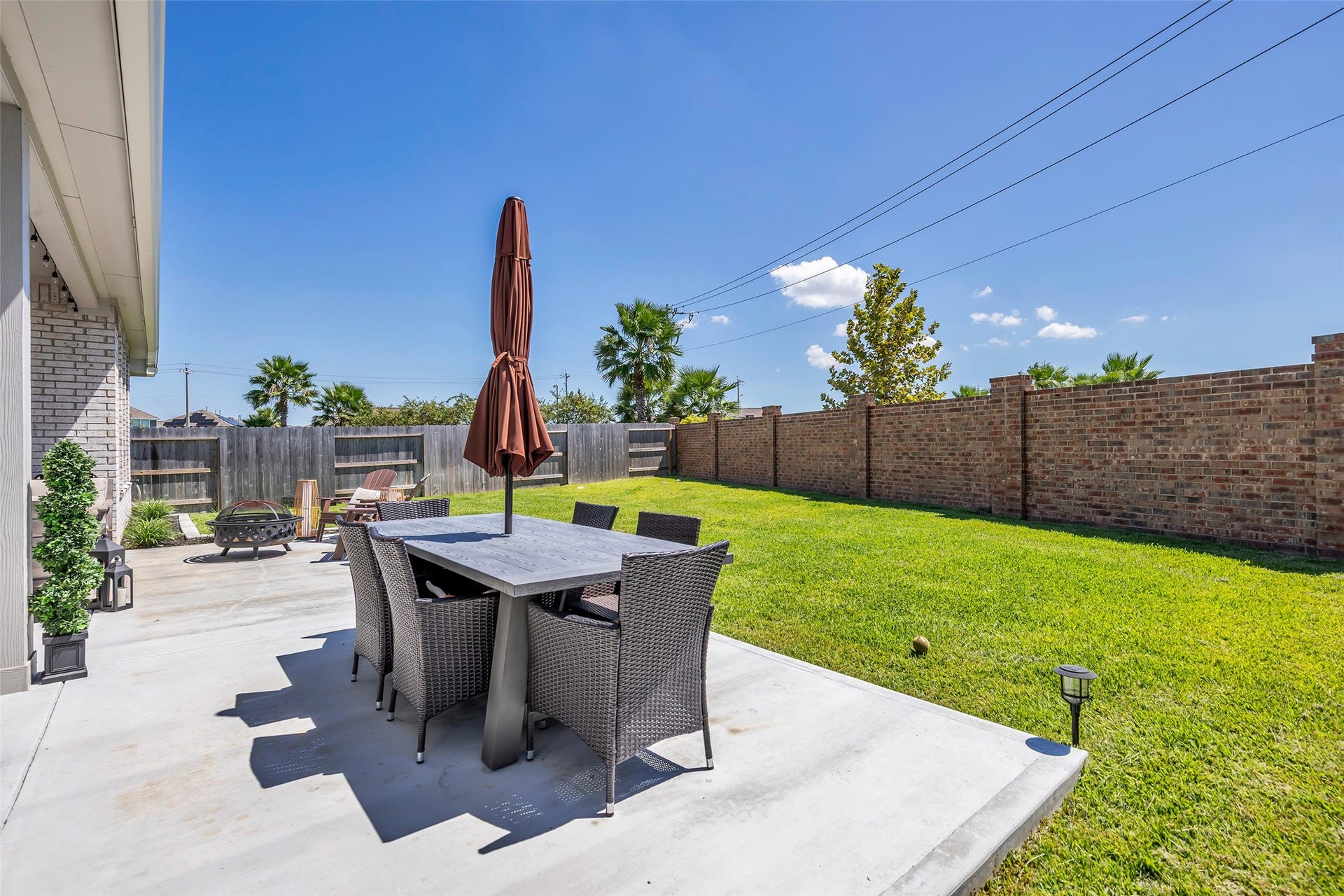 13213 Harbor Point Drive, Texas City, TX 77539 Spacious backyard patio featuring a stylish dining set, lush green lawn, and a cozy fire pit area, perfect for outdoor gatherings.