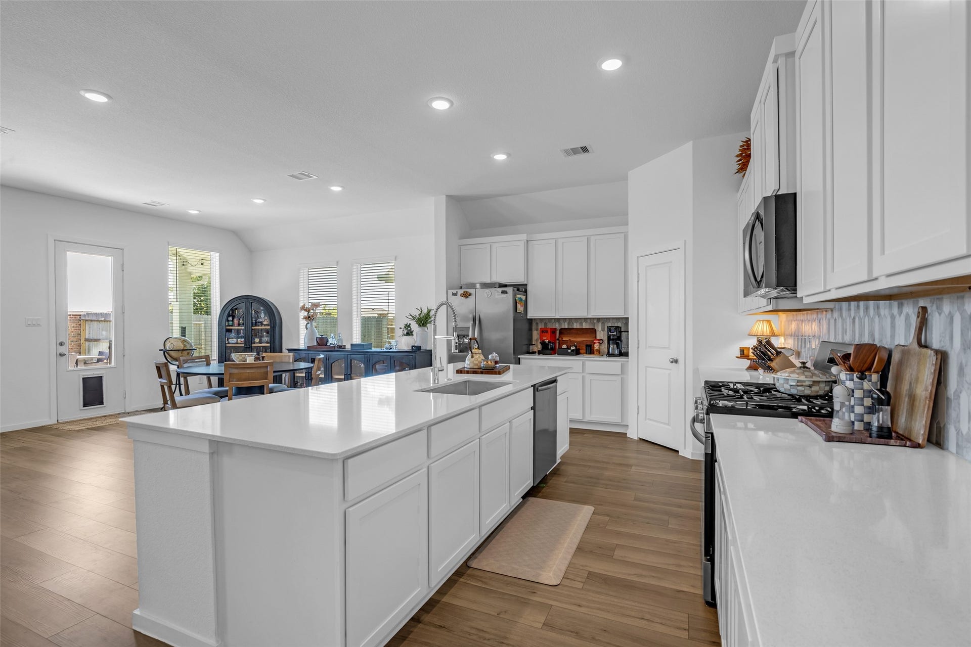 13213 Harbor Point Drive, Texas City, TX 77539 Spacious, modern kitchen with sleek white cabinetry, a large island, and stainless steel appliances, seamlessly flowing into a bright dining area.