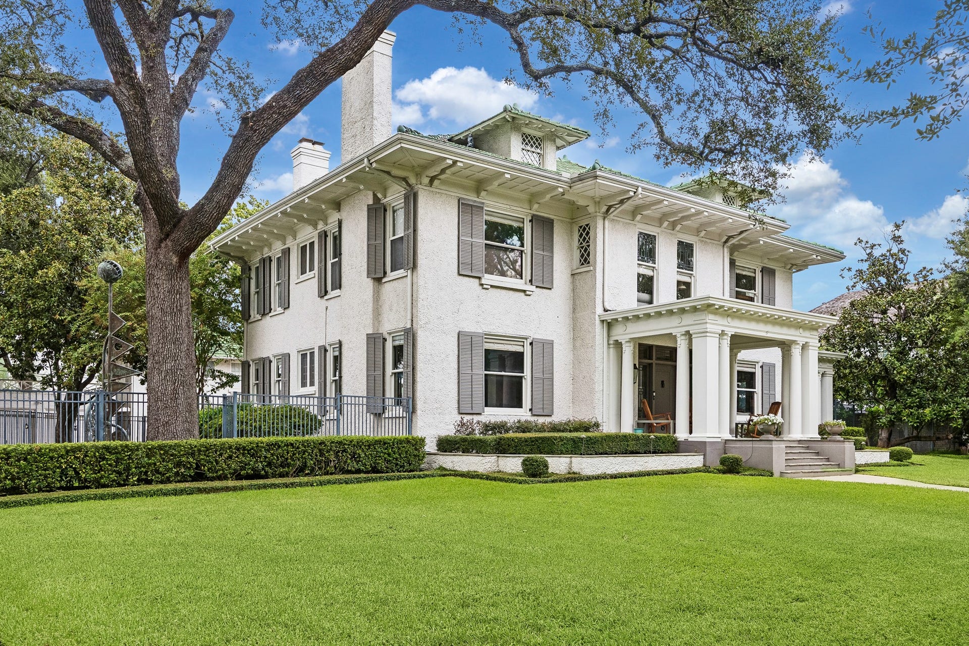 8 Courtlandt Place, Houston, TX 77006 An angled view showcases the home's original operable shutters, decorative eaves and distinctive early 20th-century craftsmanship.