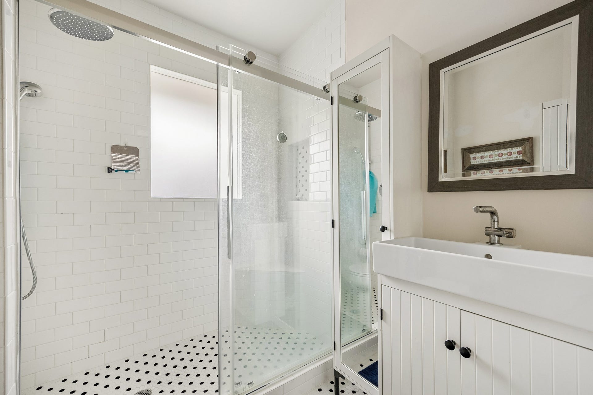8 Courtlandt Place, Houston, TX 77006 A well-appointed bath offers a glass-enclosed shower with rainfall showerhead, classic white tile and a vanity with additional storage.