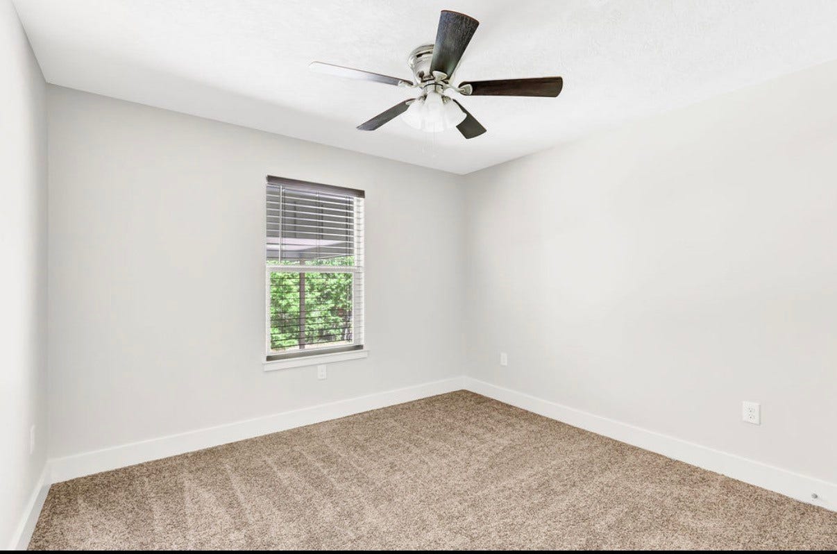 Bright and inviting bedroom with fresh neutral tones, cozy carpeting, and a ceiling fan for ultimate comfort.