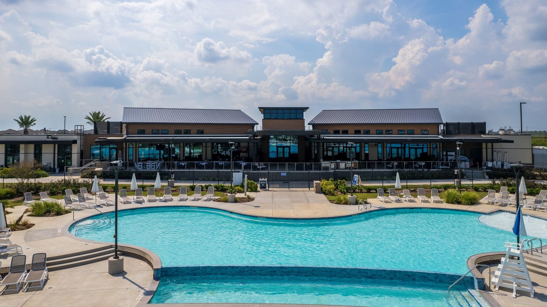 13716 Windward Mist Drive, La Marque, TX 77568 Expansive resort-style pool with abundant lounge seating and a modern clubhouse overlooking the water.
