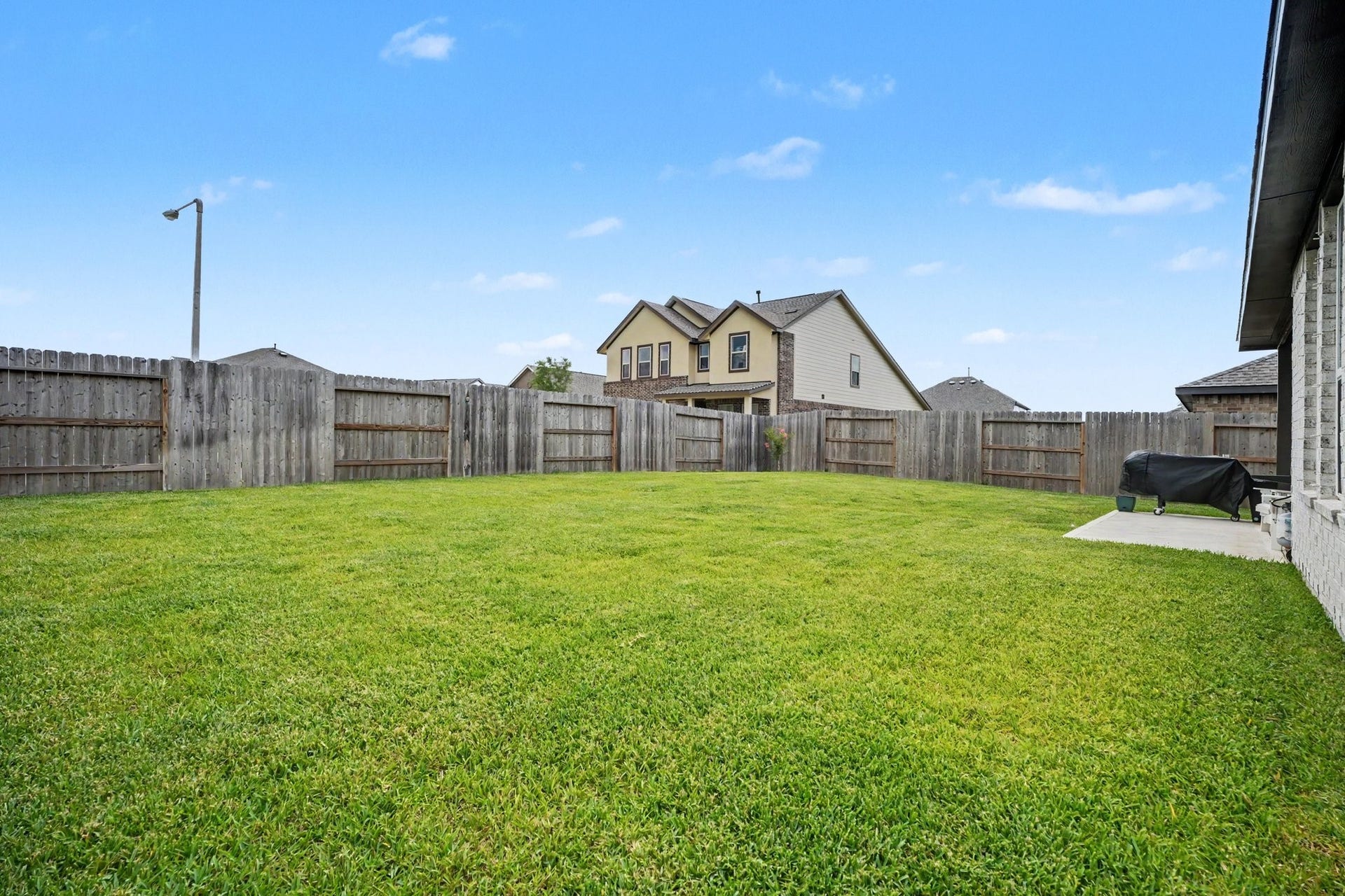 13716 Windward Mist Drive, La Marque, TX 77568 Alternate view of the backyard showcasing the spacious lawn and fully fenced yard.
