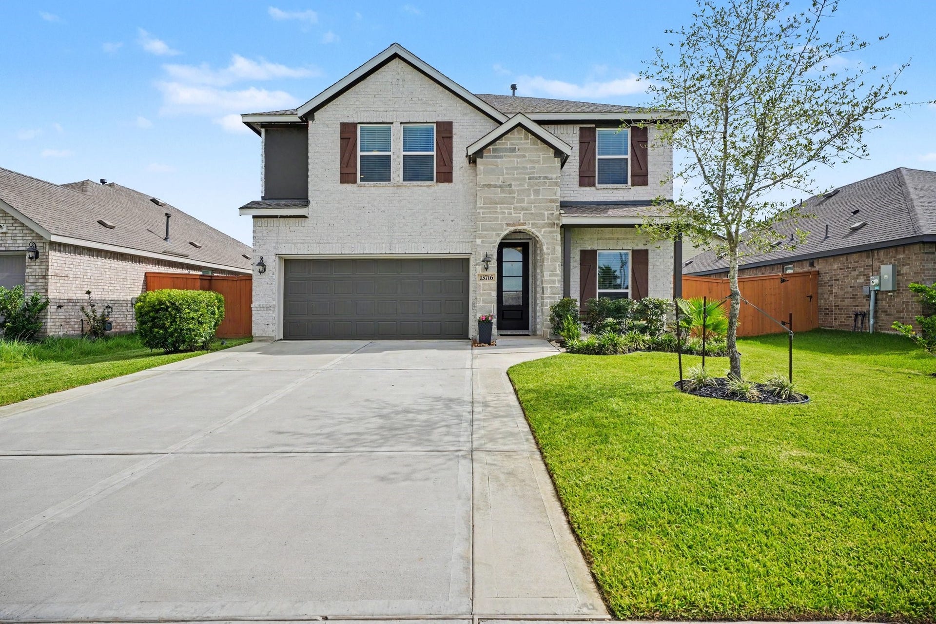 13716 Windward Mist Drive, La Marque, TX 77568 Beautiful two-story brick and stone elevation with a spacious driveway, manicured landscaping, and inviting curb appeal.