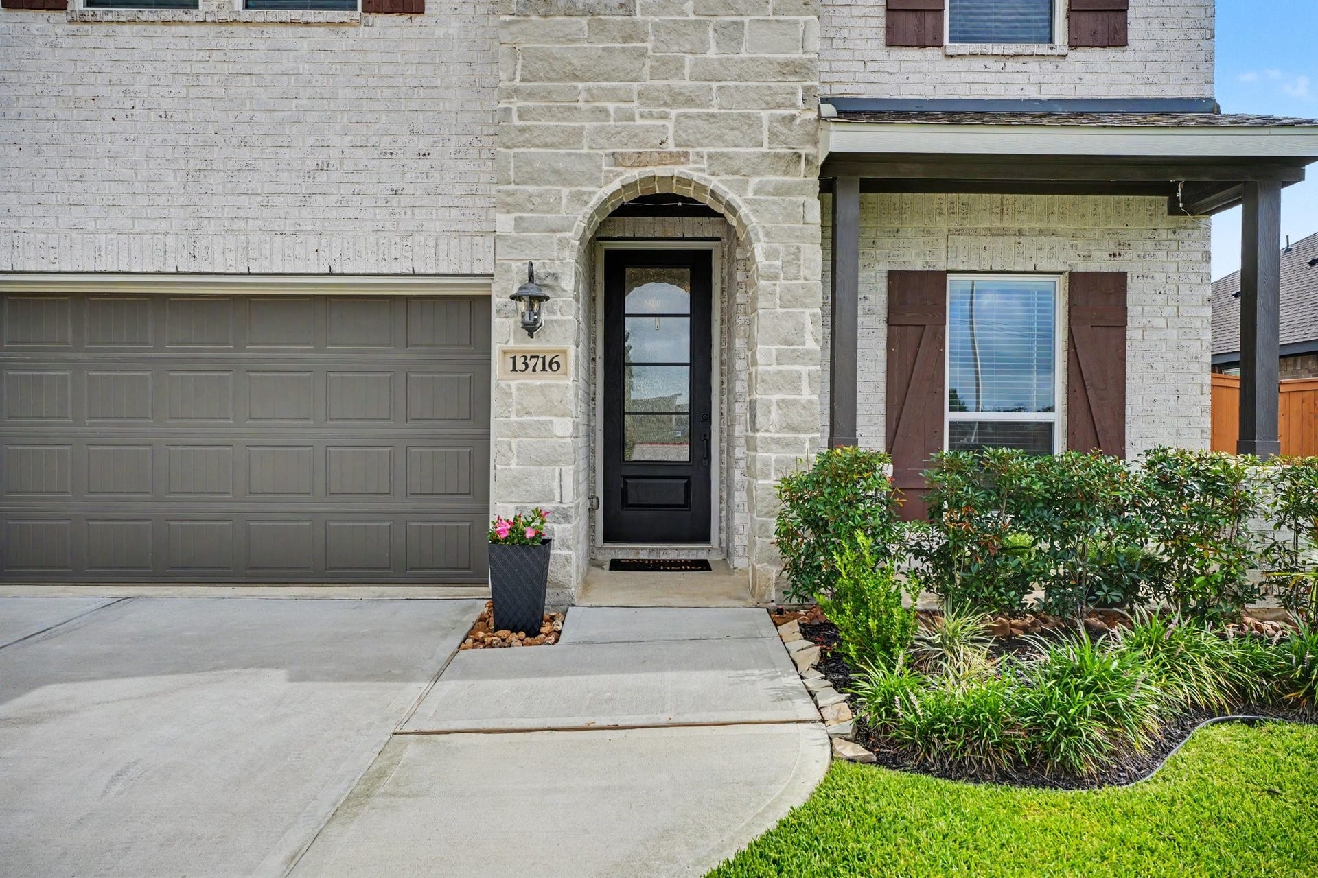 13716 Windward Mist Drive, La Marque, TX 77568 Welcoming covered entry with stone accents, decorative landscaping, and a stylish front door that creates a warm first impression.