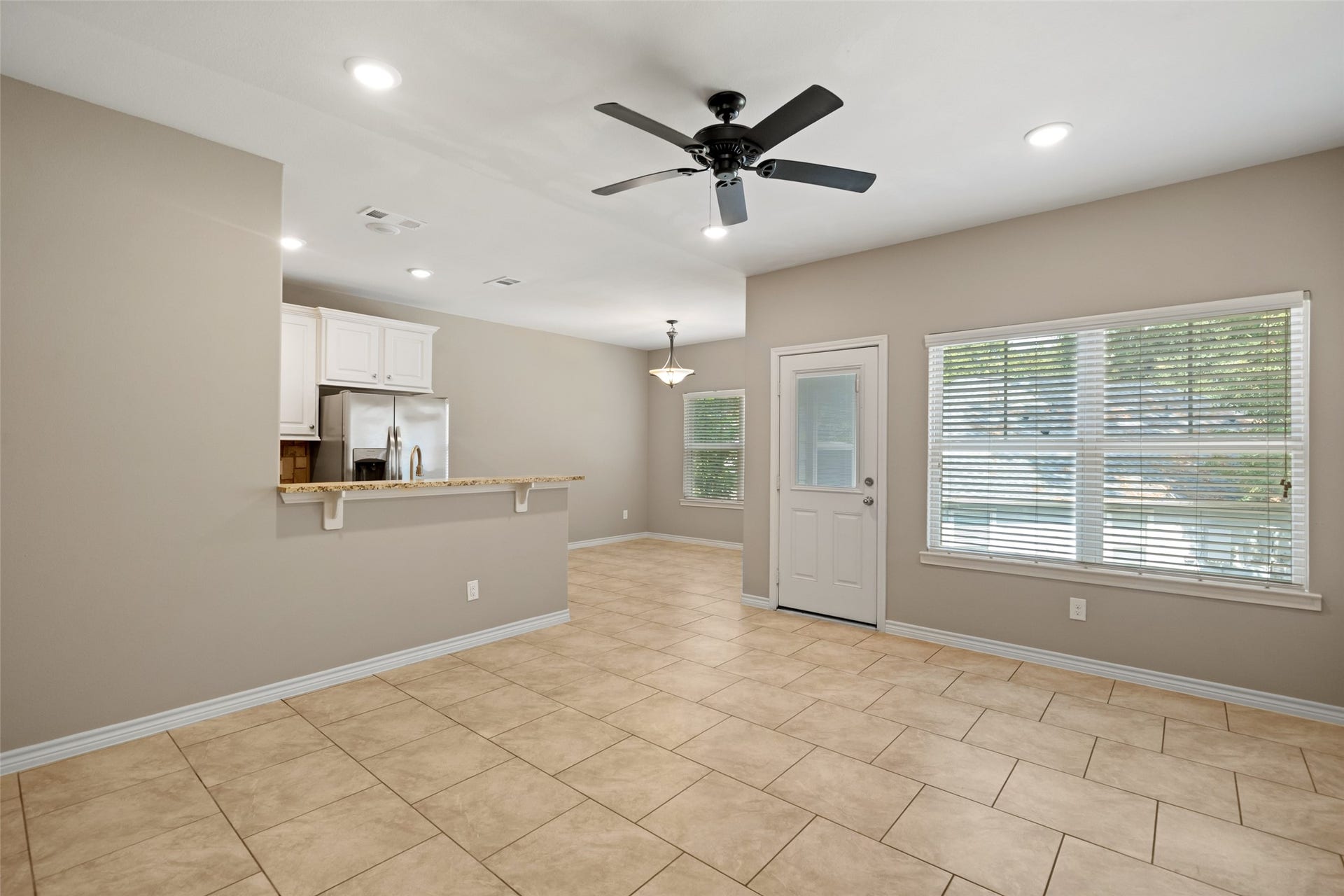 Each side has an identical open living room with tile flooring, ceiling fan, window blinds throughout, and plenty of natural light.