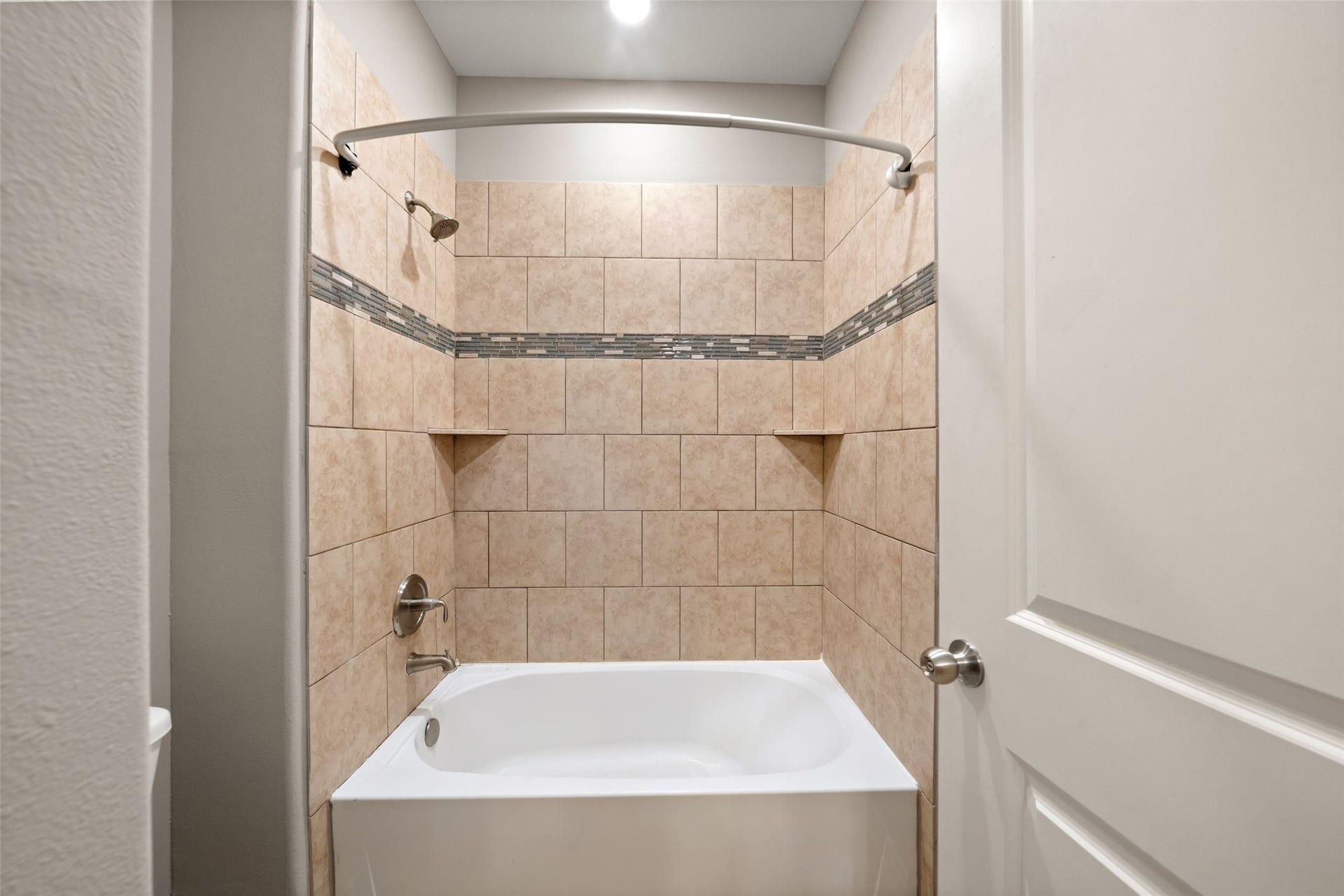 Tiled tub/shower within the bathroom. Tub/commode are separate from the sink/vanity area.