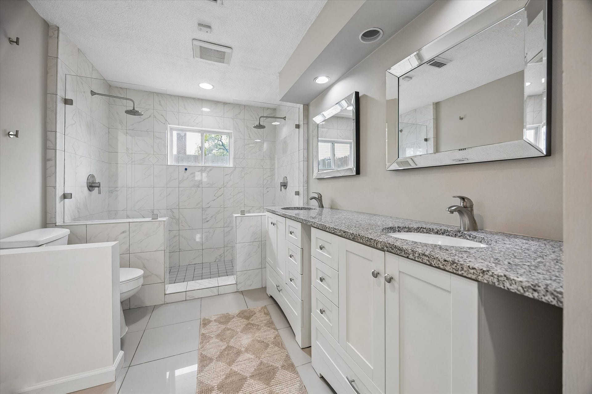 The primary ensuite bath feels like a private spa, featuring a dual-sink vanity and a spacious walk-in shower equipped with two showerheads.