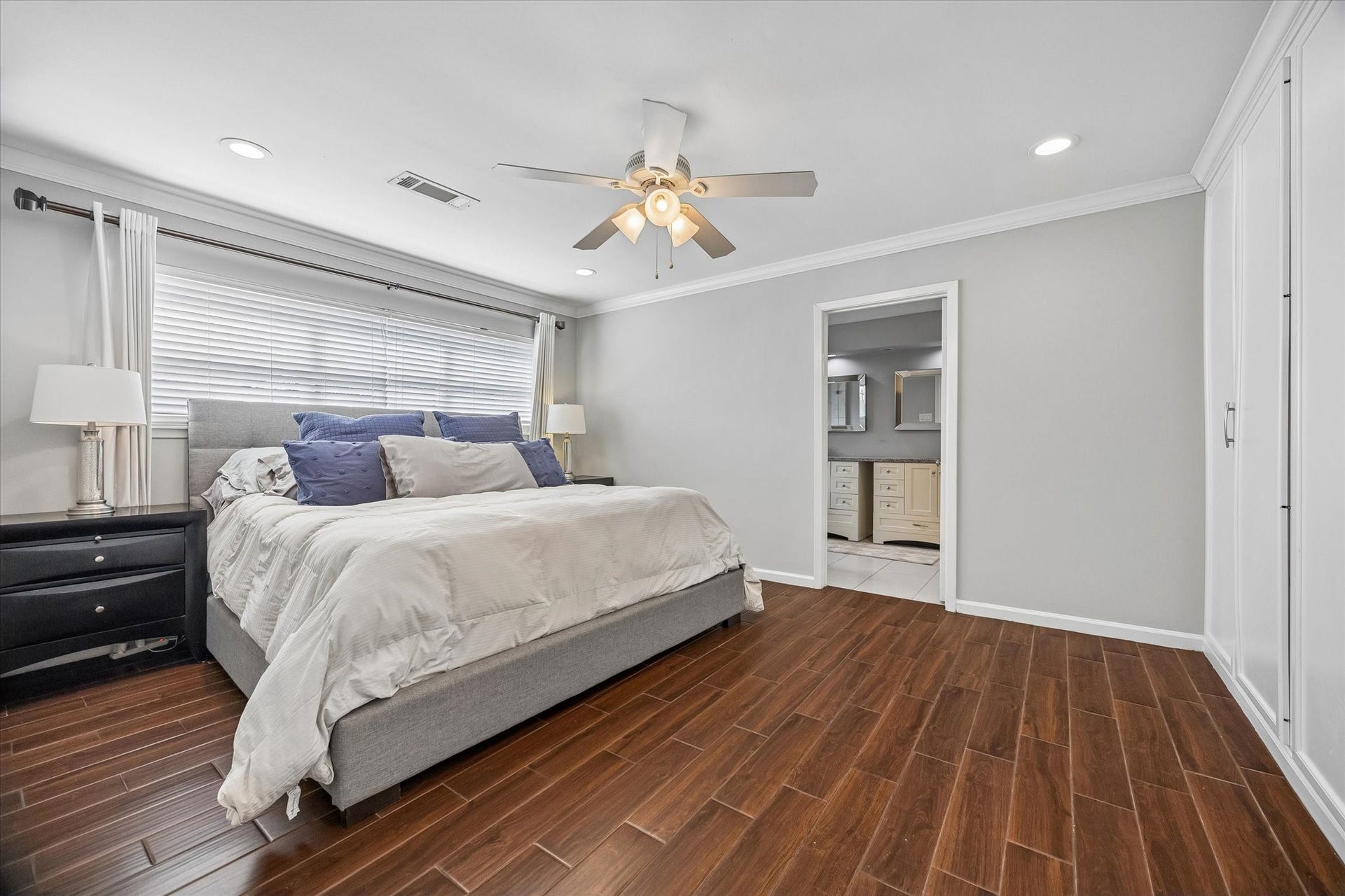 The primary suite serves as a true retreat, featuring wood-look tile flooring and elegant crown molding. Youll find an abundance of storage within the impressive wall of built-in closet space.