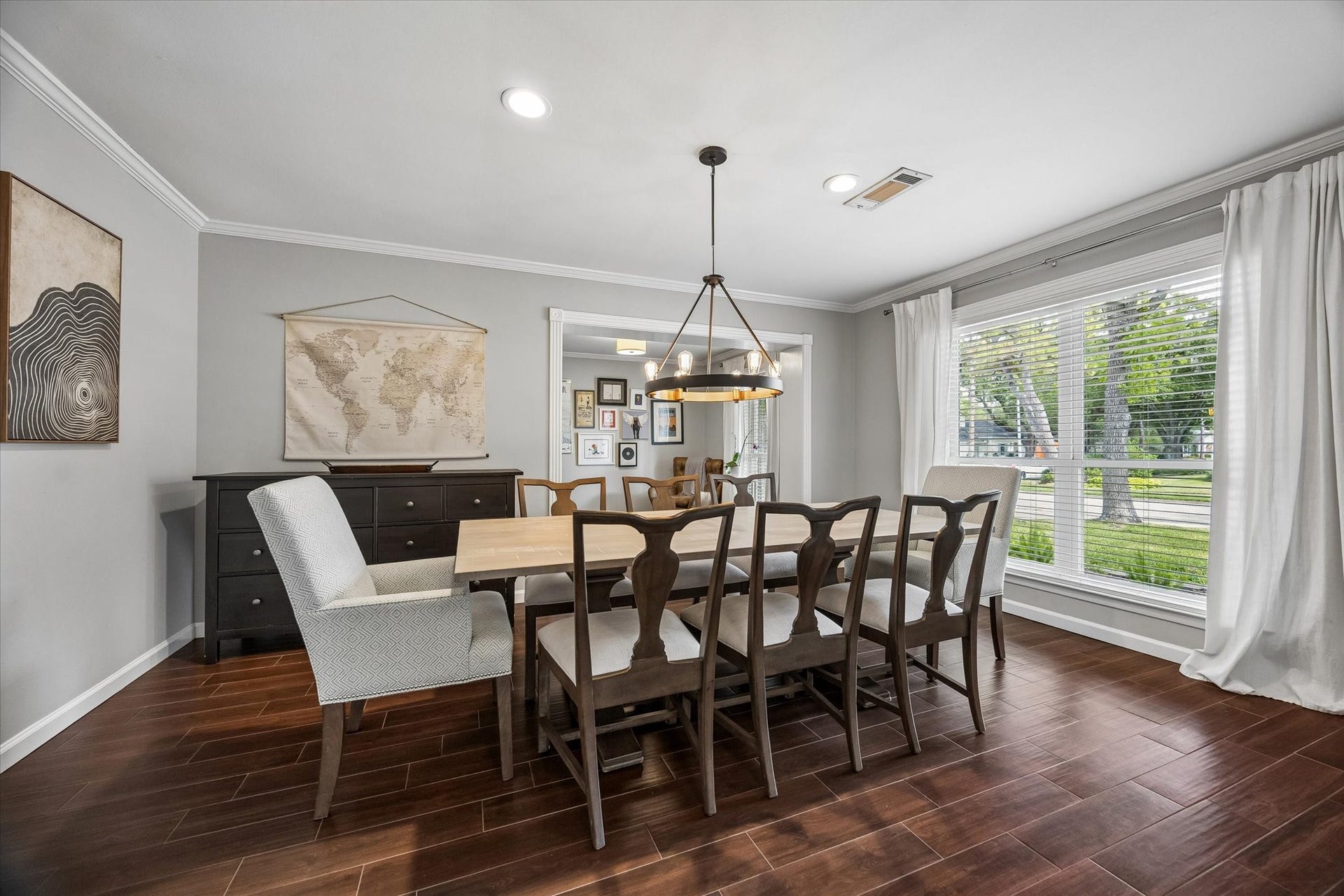 Formal dining featuring crown molding, recessed lighting, and views of the landscaped front yard. It flows seamlessly into a versatile office space, where French doors could easily be added for extra privacy.