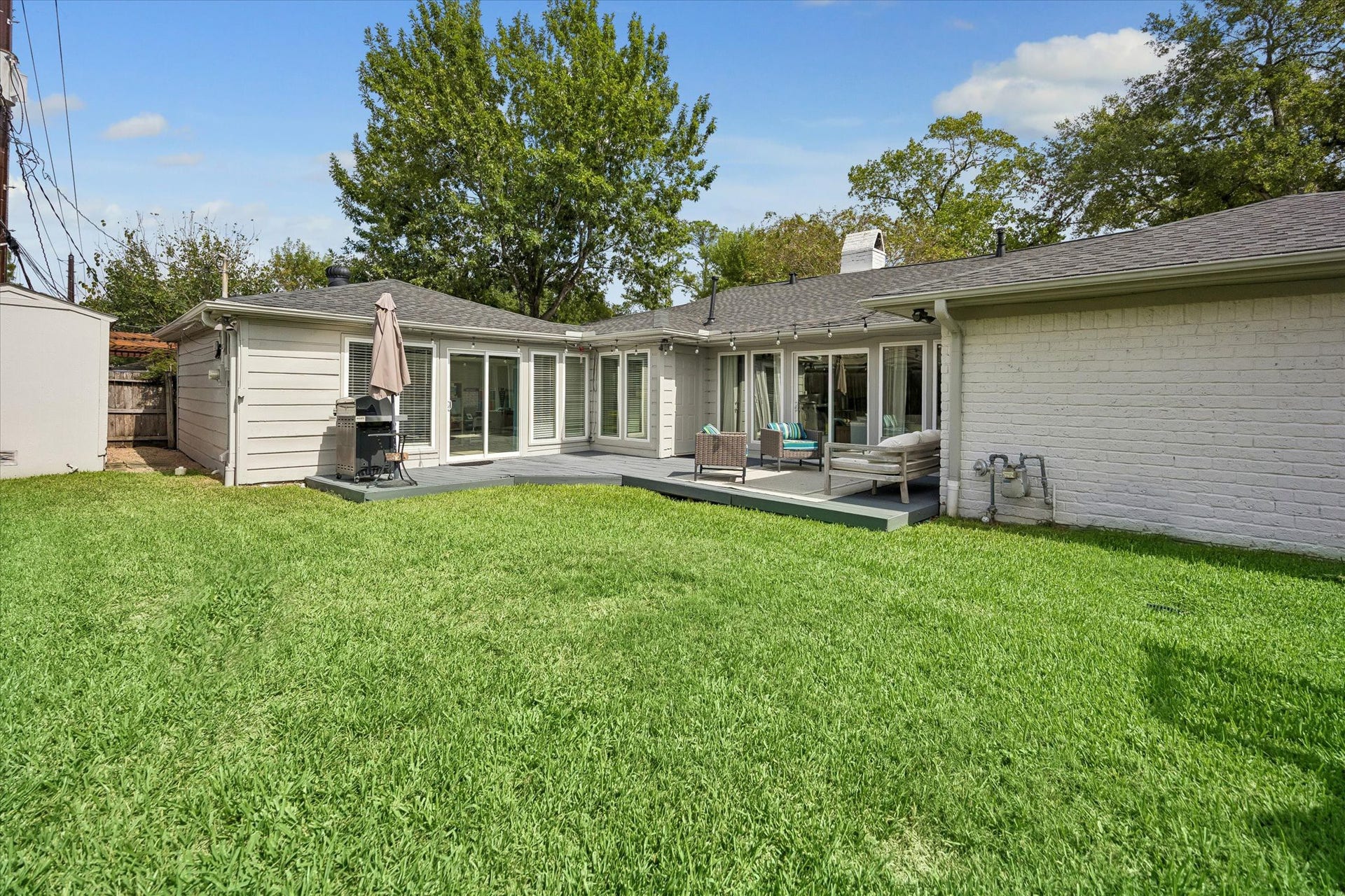 The backyard offers plenty of green space with a custom deck for outdoor seating and ample room for customization.