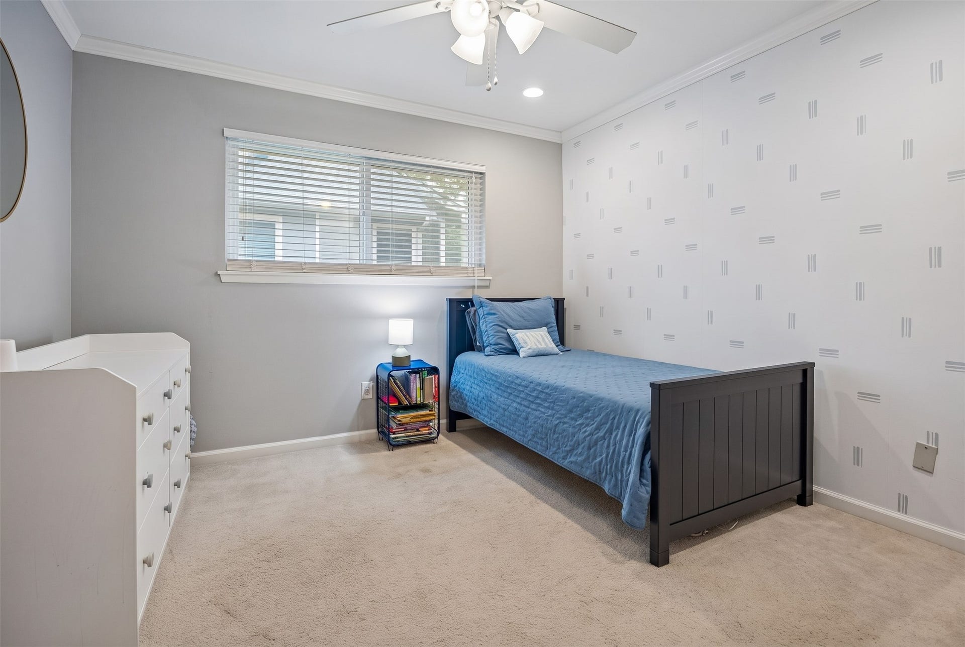 Guest bedroom with charming wallpaper, crown molding, and ceiling fan.