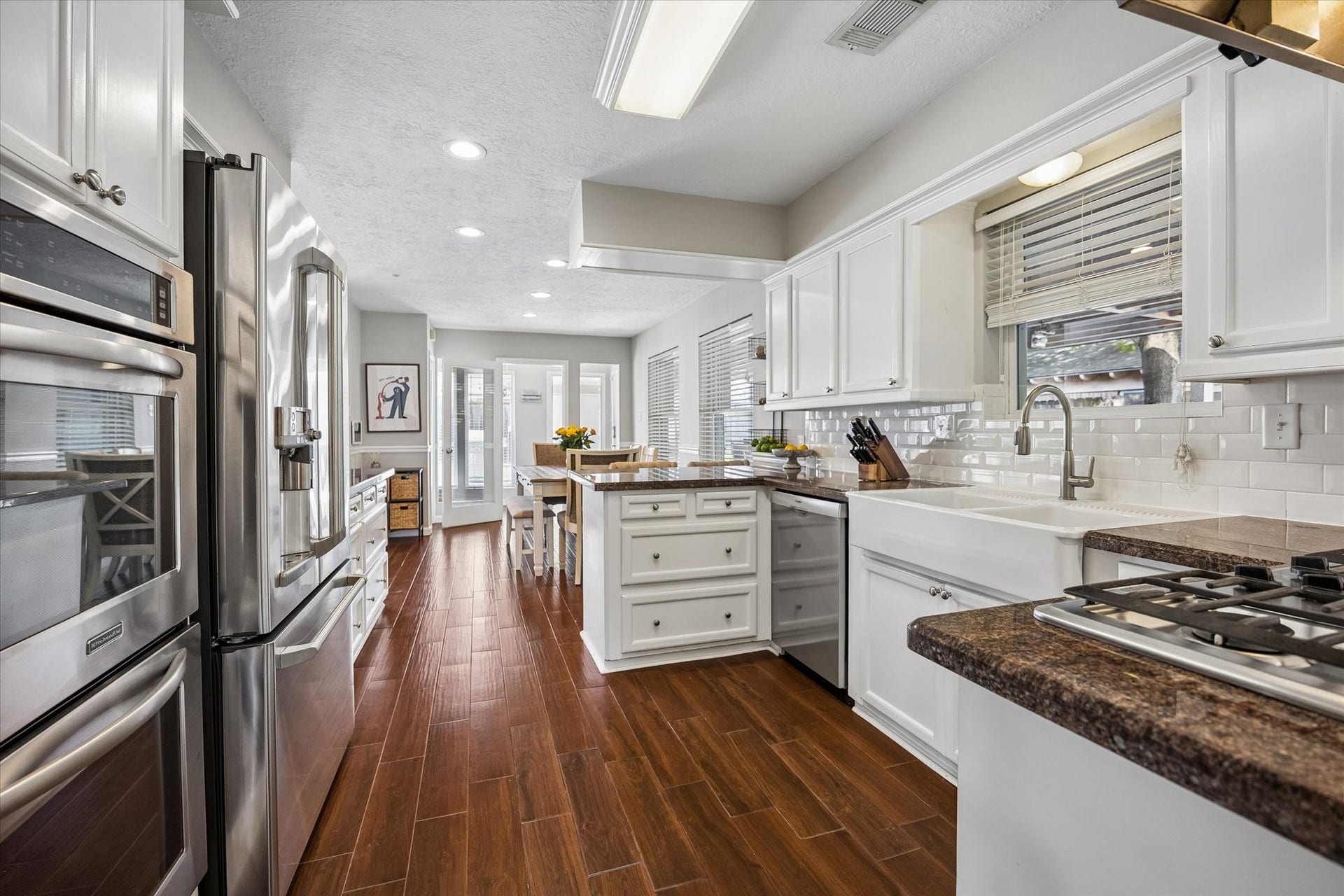 Another perspective of the kitchen showing the double ovens and Farmhouse sink. The space flows effortlessly into a sunlit breakfast area, which connects to a versatile fourth bedroom that doubles perfectly as a flex space.