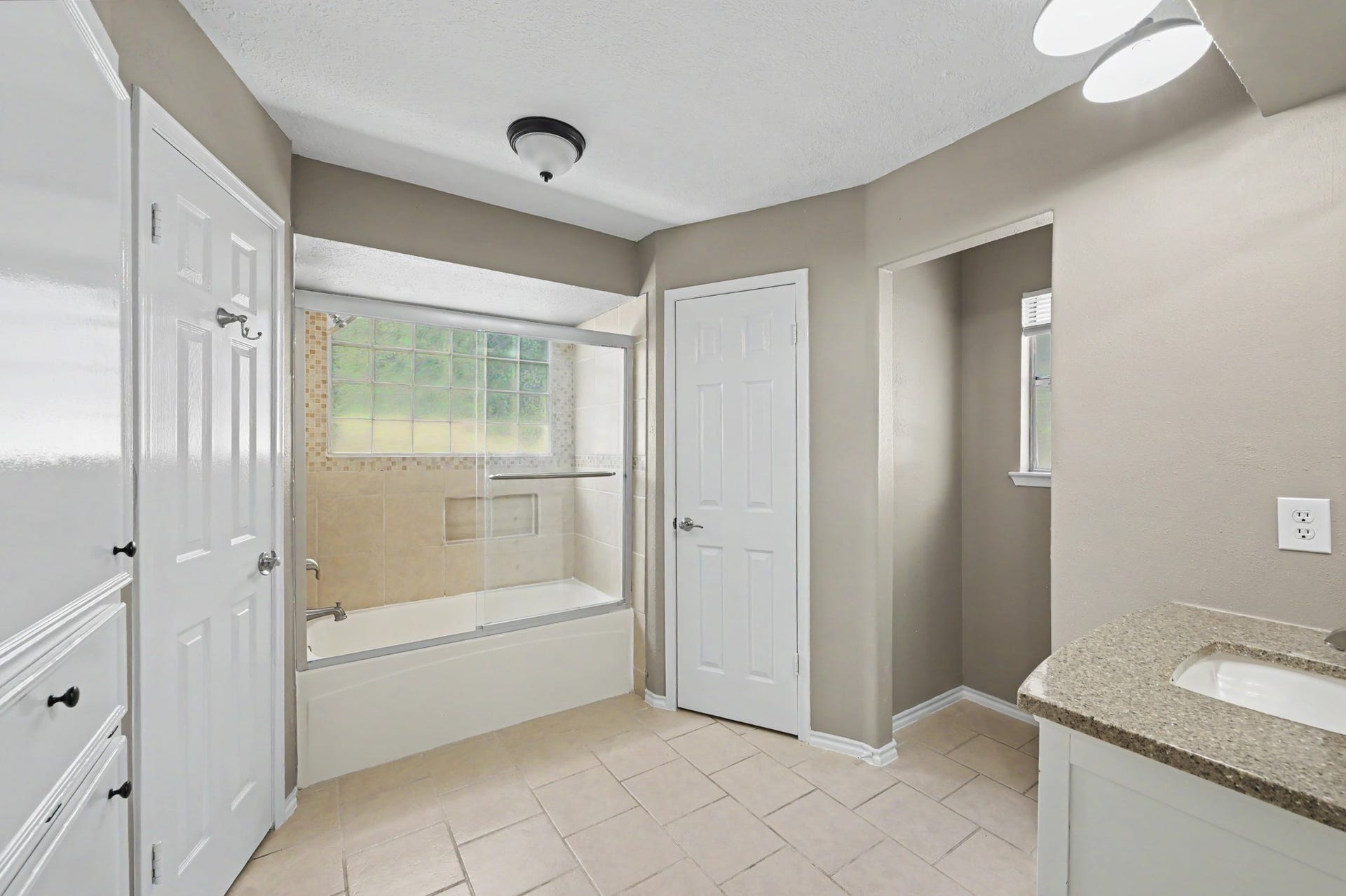 A spacious bathroom with a tub and shower combo, generous counter space, and plenty of storage.
