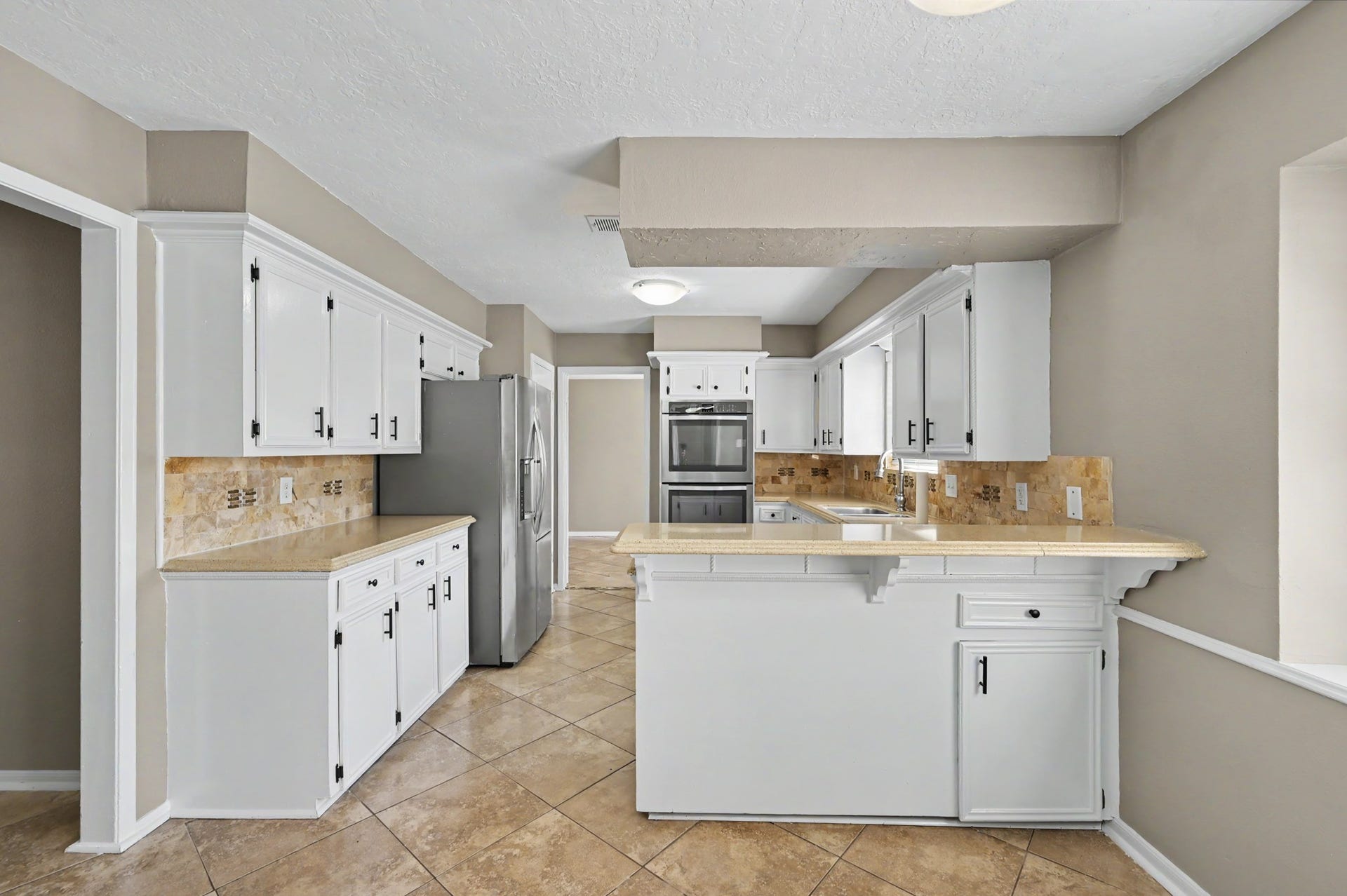Updated kitchen featuring white cabinetry, stainless steel appliances, and generous counter space.