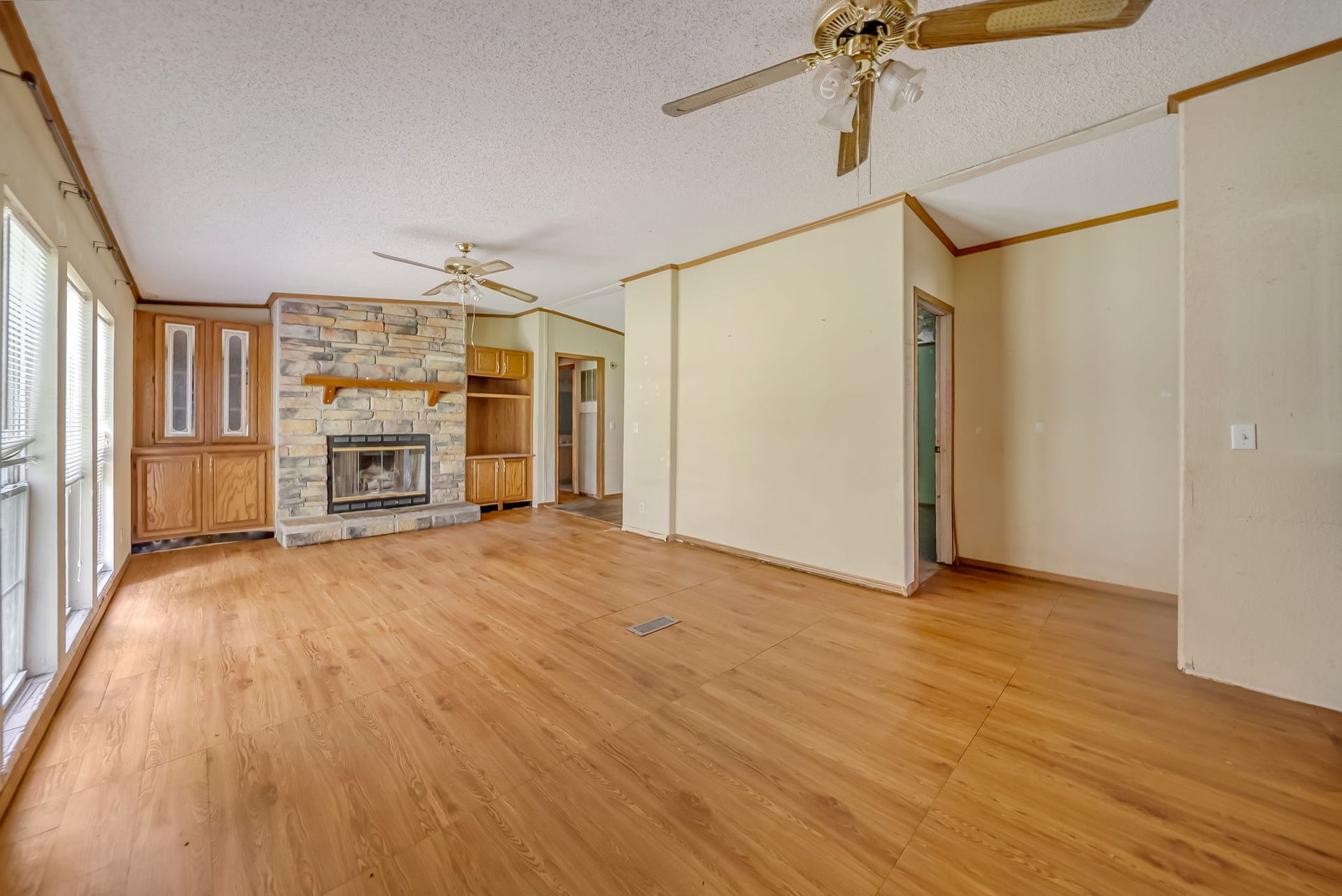 The spacious family room is centered around a charming floor-to-ceiling stone fireplace with built-in cabinetry, creating a warm and inviting space for everyday living and entertaining.