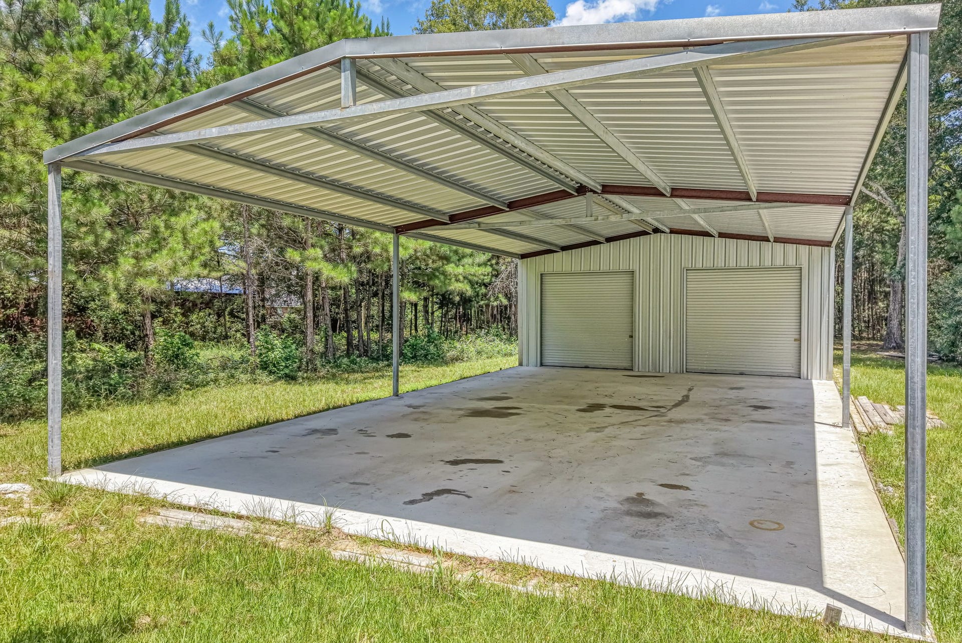 The metal building features a 30' x 50' enclosed workshop with two roll-up doors and a 30' x 50' covered open bay.