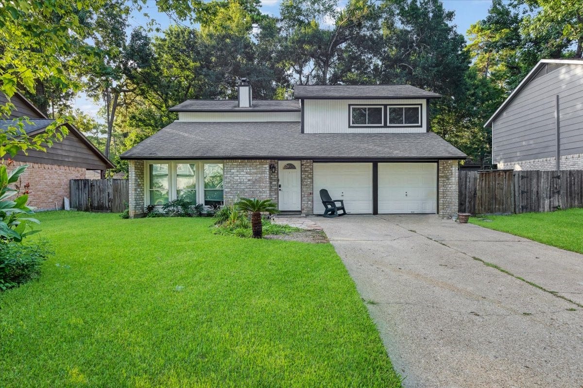 Welcoming two-story home with a two-car garage, mature shade trees, established landscaping, and a spacious green front lawn.