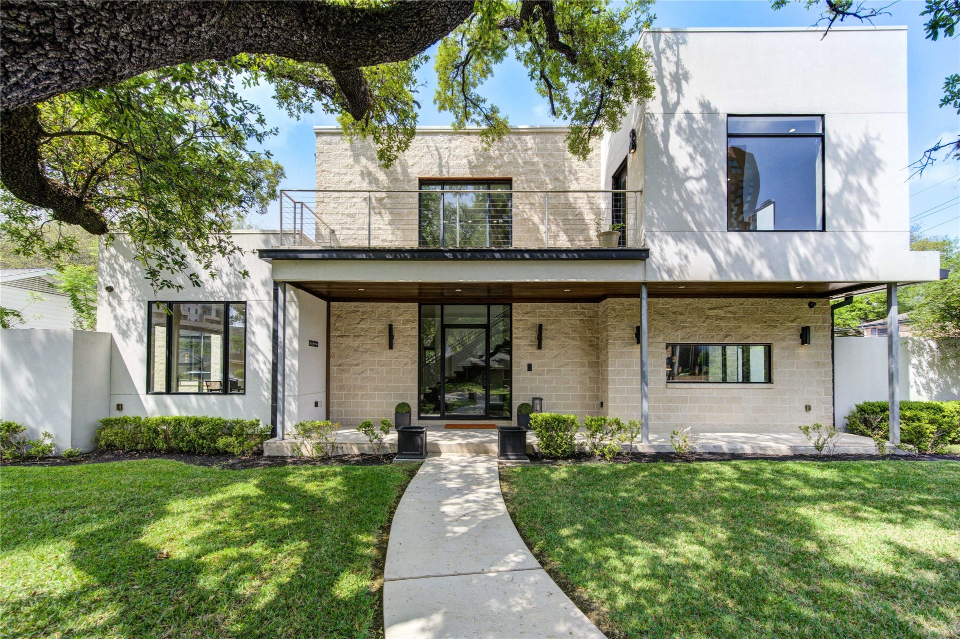 5202 Chesapeake Way, Houston, TX 77056 A sleek facade with large windows, a clean white exterior, and stone accents. The entrance is framed by a spacious porch and well-maintained landscaping, creating a welcoming atmosphere.