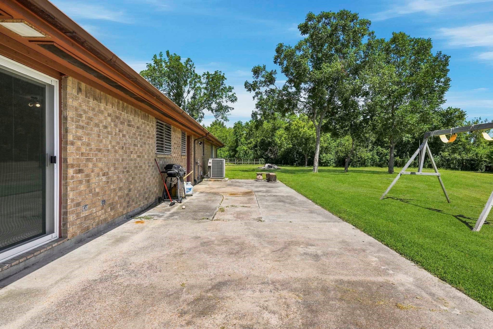 16101 Bluebird Street, Santa Fe, TX 77517 Spacious backyard with a patio area, perfect for outdoor entertaining, complemented by lush green lawn and mature trees for added privacy.