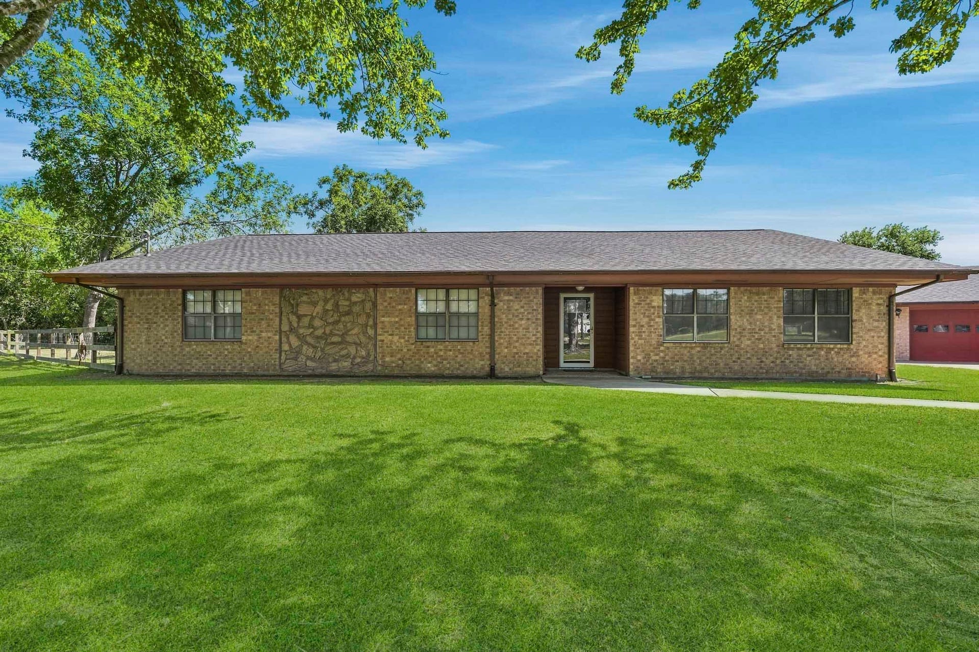 16101 Bluebird Street, Santa Fe, TX 77517 Charming single-story brick home with a spacious front lawn and mature trees, offering a peaceful and inviting atmosphere.
