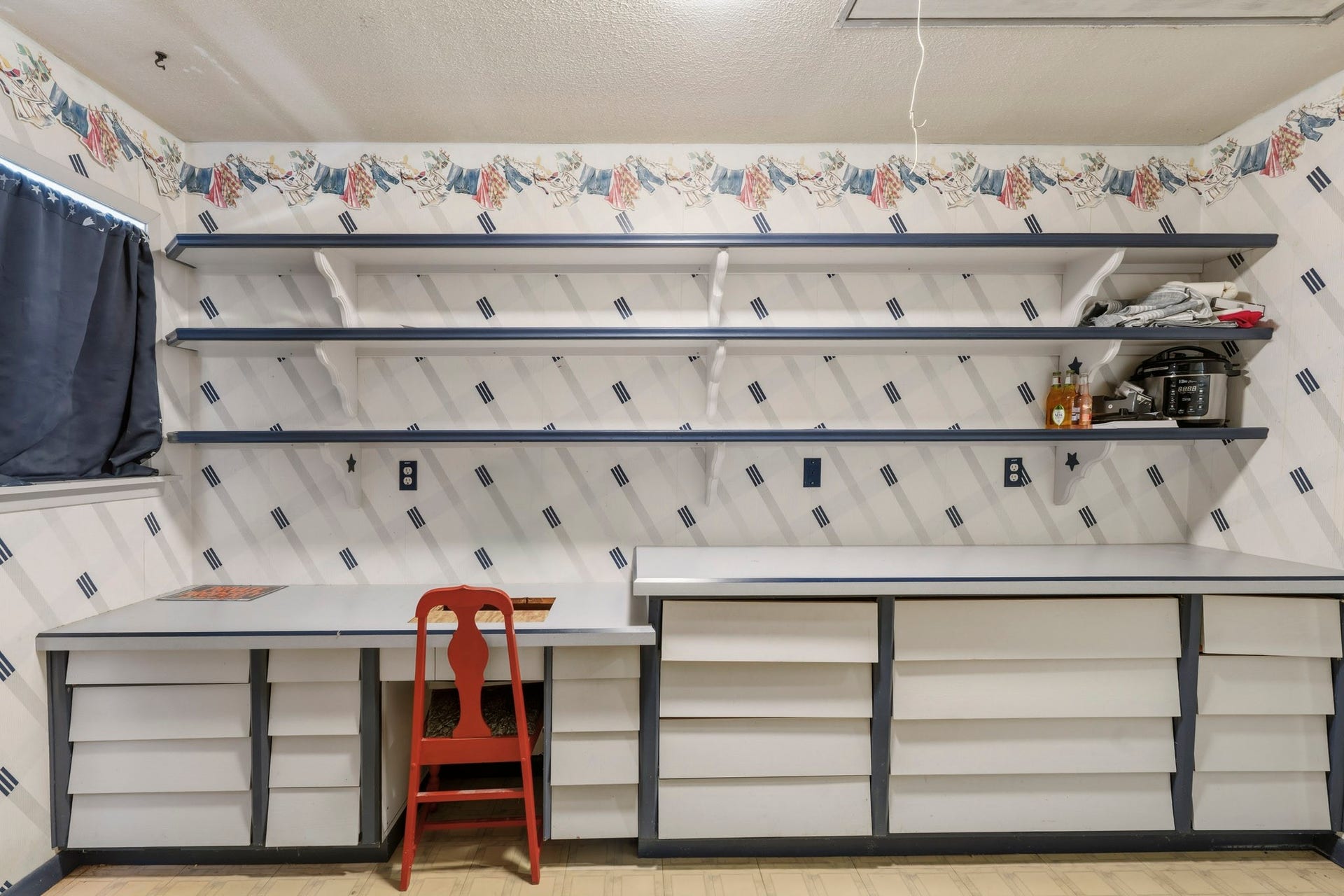 16101 Bluebird Street, Santa Fe, TX 77517 Charming workspace features ample shelving and storage with a playful wallpaper design, perfect for crafting or home projects.