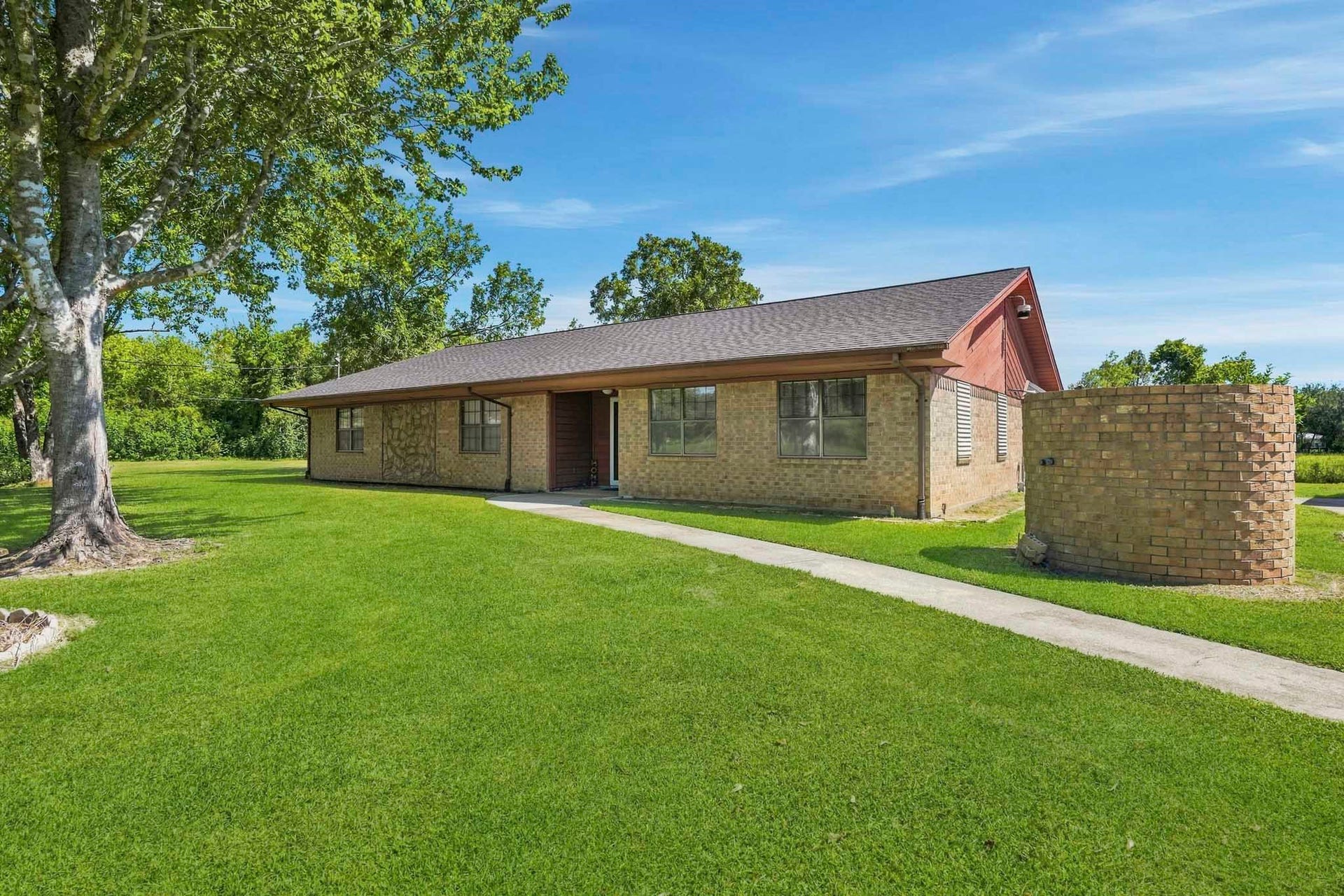 16101 Bluebird Street, Santa Fe, TX 77517 Charming brick ranch-style home nestled on a spacious, lush lawn with mature trees offering shade and privacy.
