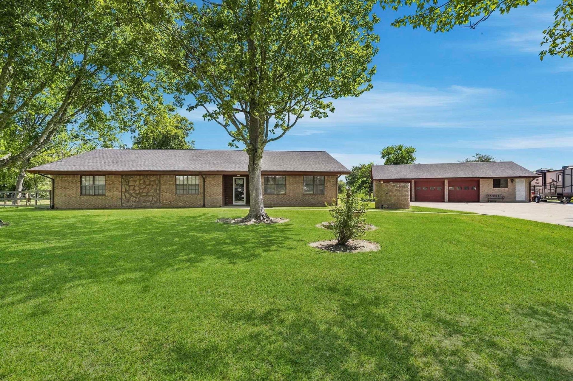 16101 Bluebird Street, Santa Fe, TX 77517 Charming brick ranch-style home with a spacious front lawn and mature trees, featuring a detached garage and ample driveway space.