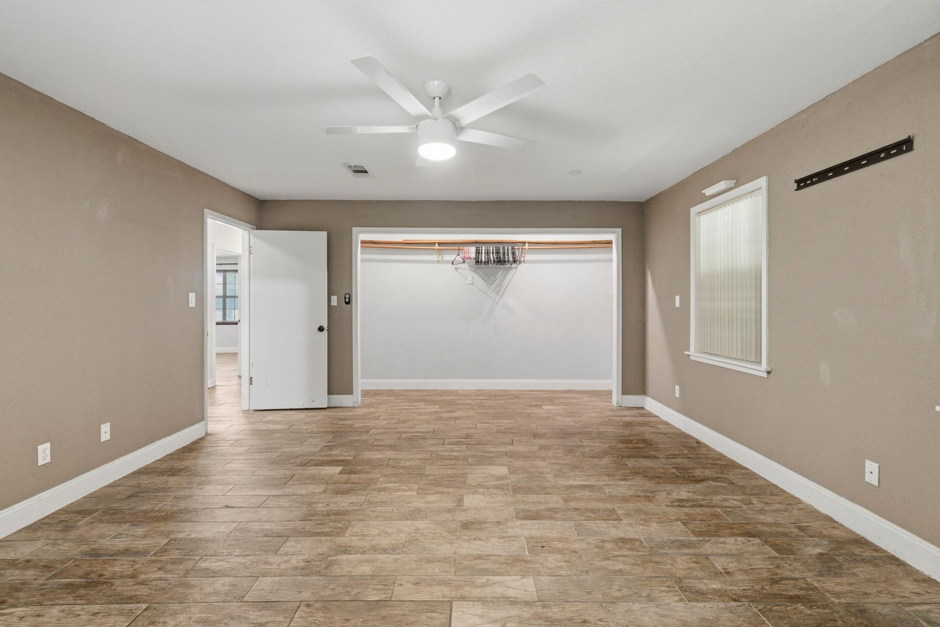 16101 Bluebird Street, Santa Fe, TX 77517 Spacious primary bedroom featuring tile flooring and a ceiling fan, with an adjacent walk-in closet for ample storage.