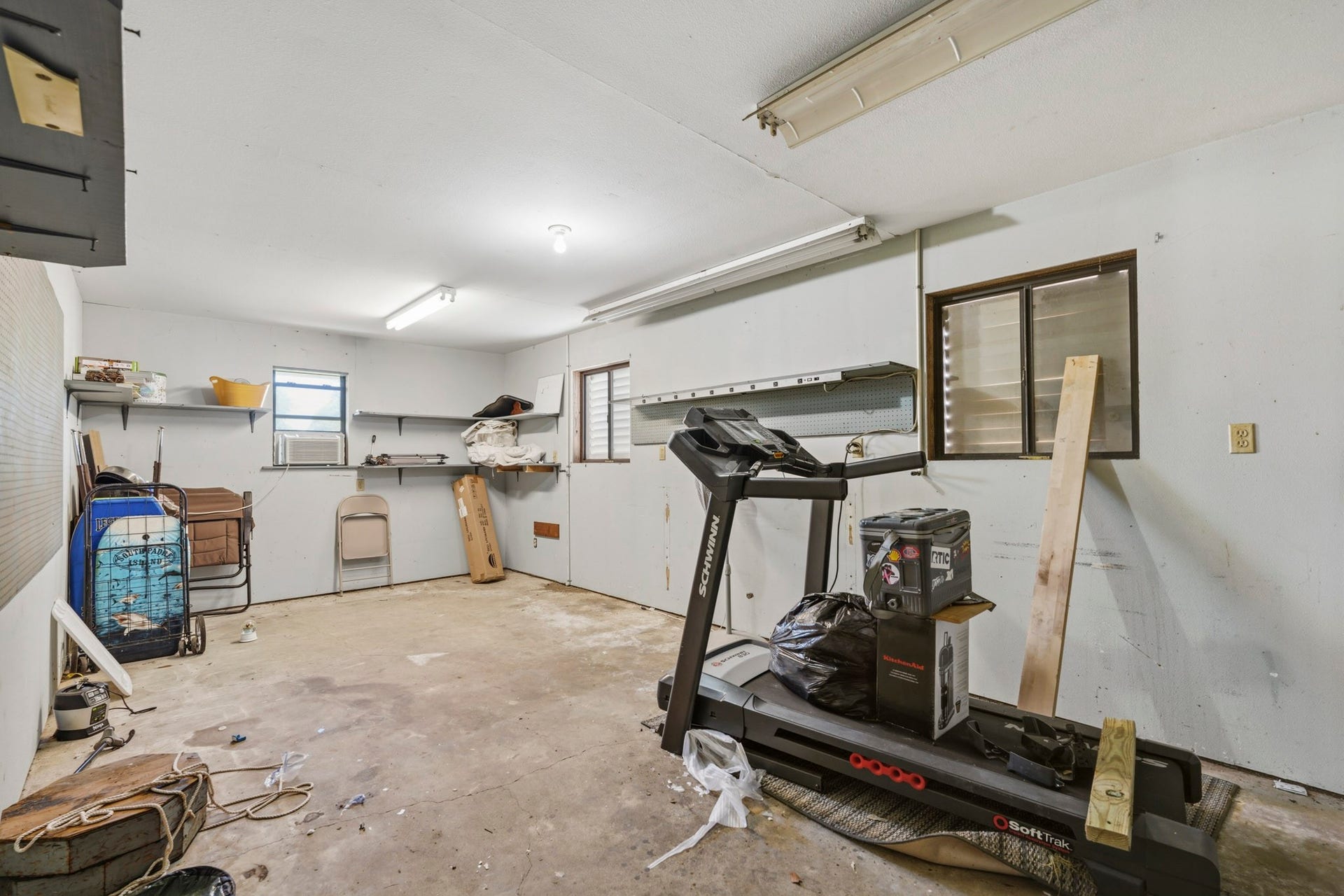 16101 Bluebird Street, Santa Fe, TX 77517 Spacious garage with ample storage options, featuring built-in shelves and windows for natural light. Perfect for a workshop or home gym setup.