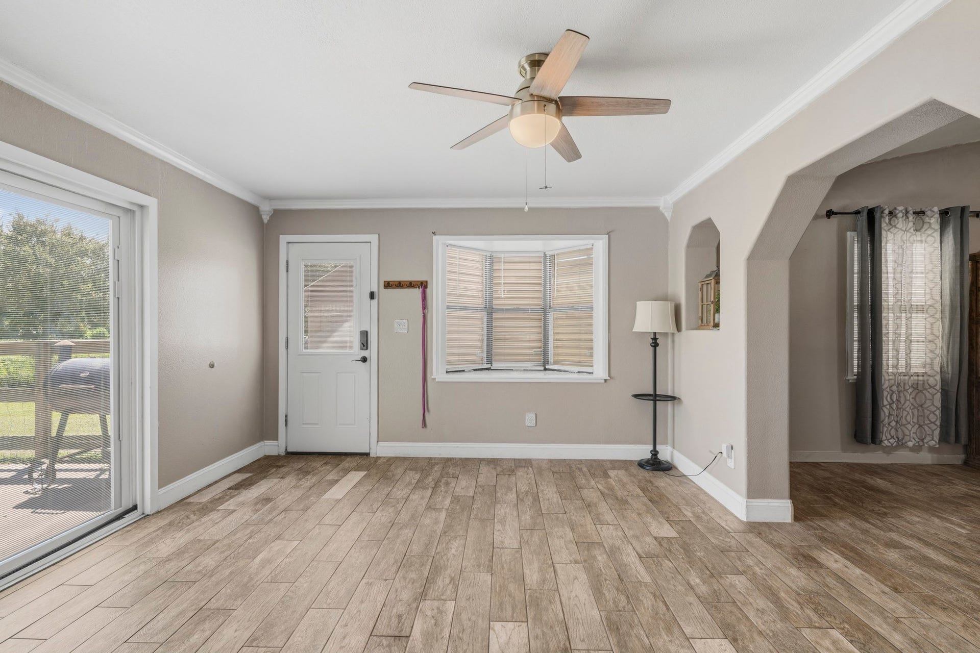 16101 Bluebird Street, Santa Fe, TX 77517 Bright and inviting space with wood-look flooring, a ceiling fan, and ample natural light from large windows and a glass door leading to the outdoor area.