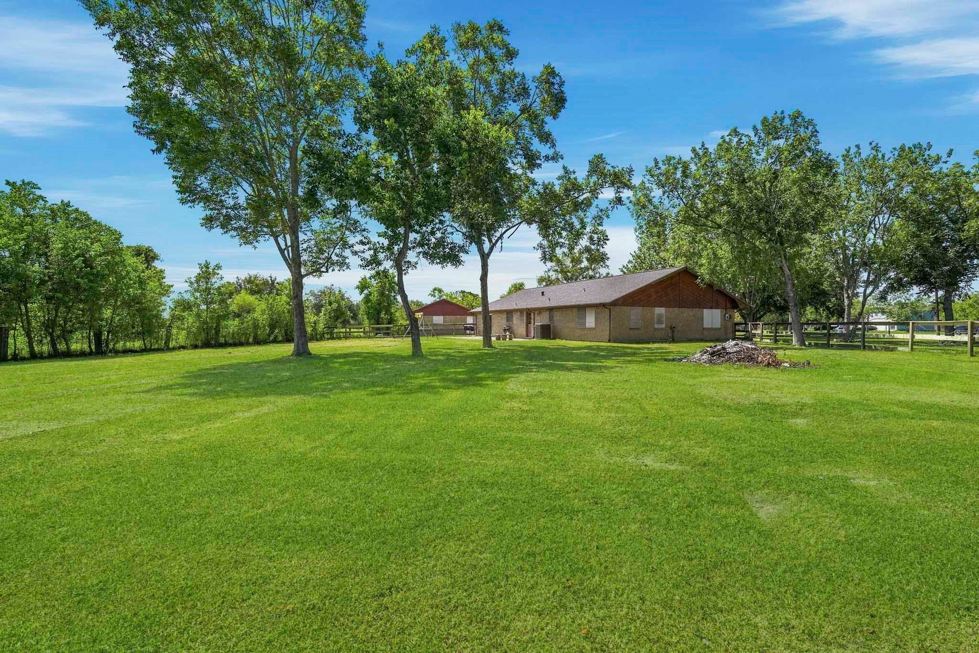 16101 Bluebird Street, Santa Fe, TX 77517 Expansive, lush backyard with mature trees and a charming single-story home, perfect for tranquil country living.