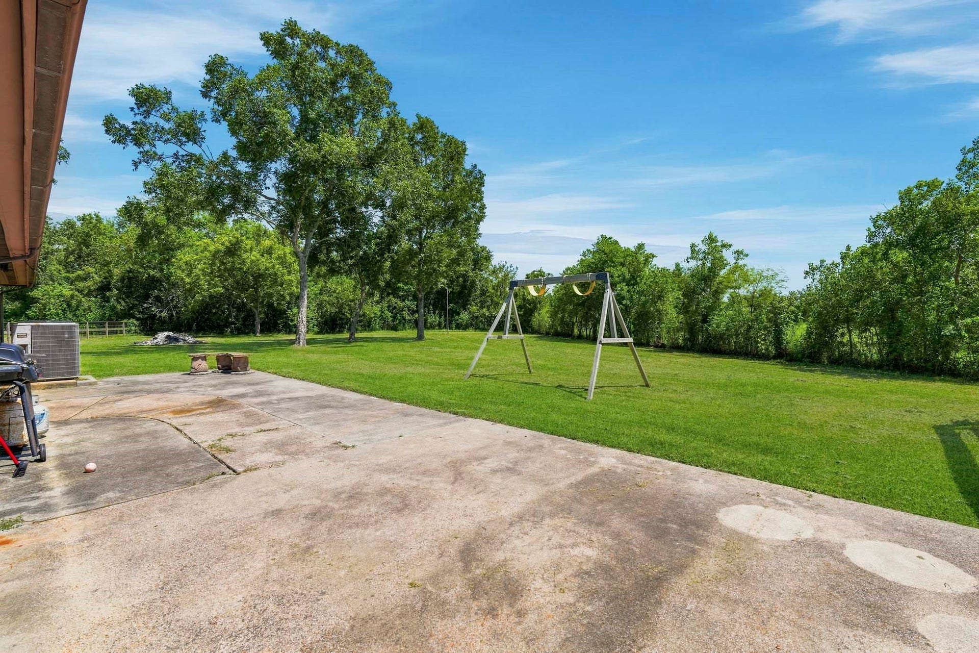 16101 Bluebird Street, Santa Fe, TX 77517 Expansive backyard with a spacious patio, lush greenery, and a swing set, perfect for outdoor activities and relaxation.
