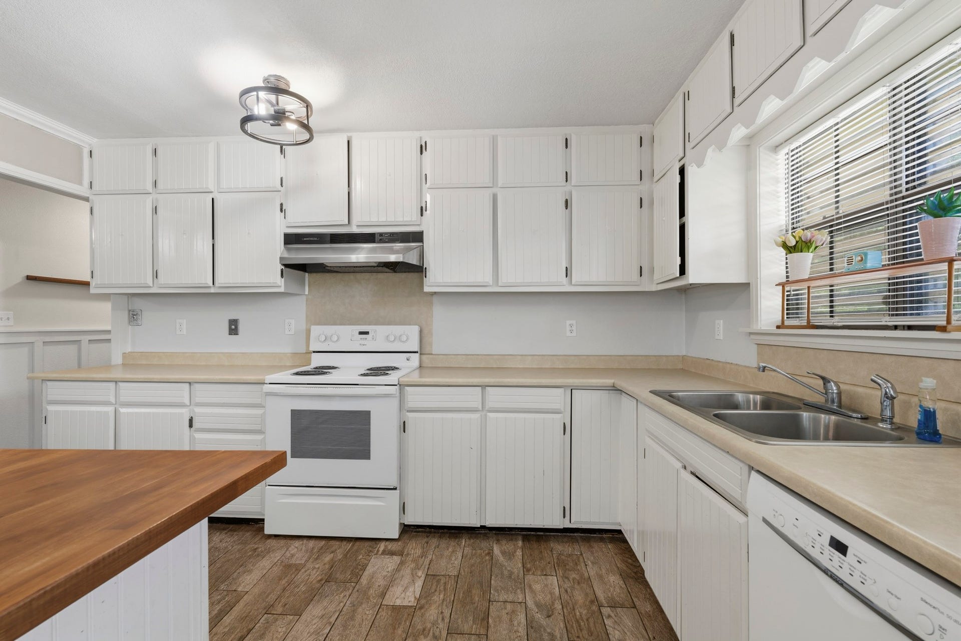 16101 Bluebird Street, Santa Fe, TX 77517 Charming kitchen with ample white cabinetry, sleek counter-tops. The large window fills the space with natural light, highlighting the modern appliances and wood-look tile flooring.
