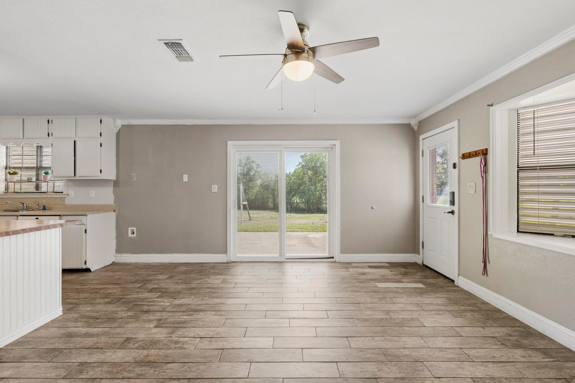 16101 Bluebird Street, Santa Fe, TX 77517 Spacious open-concept dining area featuring wood-look tile flooring, a ceiling fan, and abundant natural light from large sliding doors leading to the backyard.