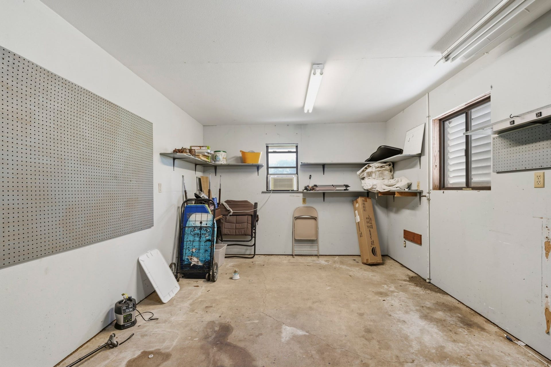 16101 Bluebird Street, Santa Fe, TX 77517 Spacious 3 car garage workshop fitted with pegboards and shelving, perfect for projects and storage.