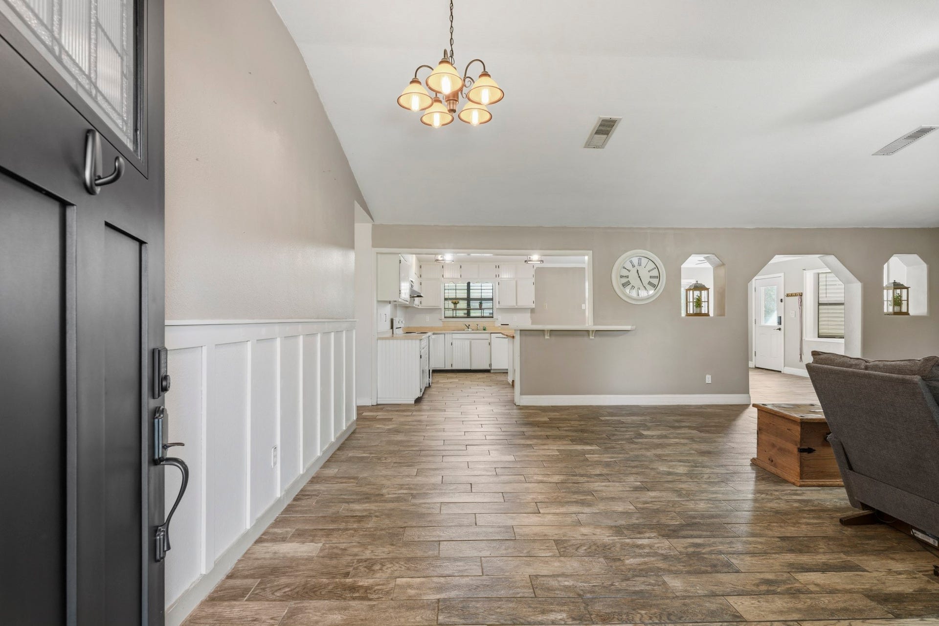 16101 Bluebird Street, Santa Fe, TX 77517 Spacious interior with vaulted ceilings and with elegant wood-look tile flooring, open layout, and a farmhouse style kitchen visible from the entryway.