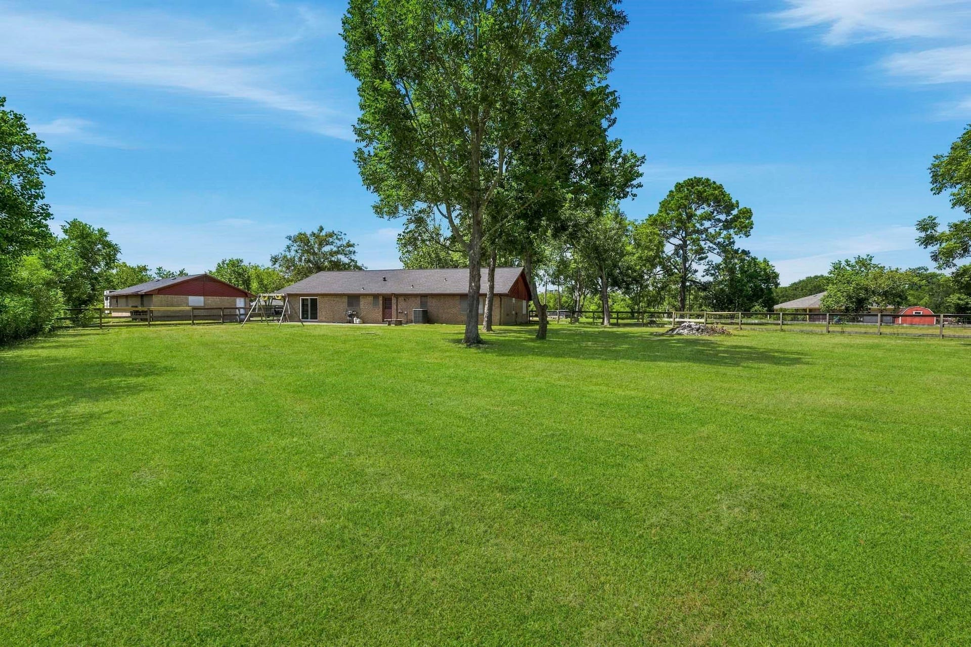 16101 Bluebird Street, Santa Fe, TX 77517 Expansive backyard with lush green lawn, mature trees, and a charming brick house offering serene country living.
