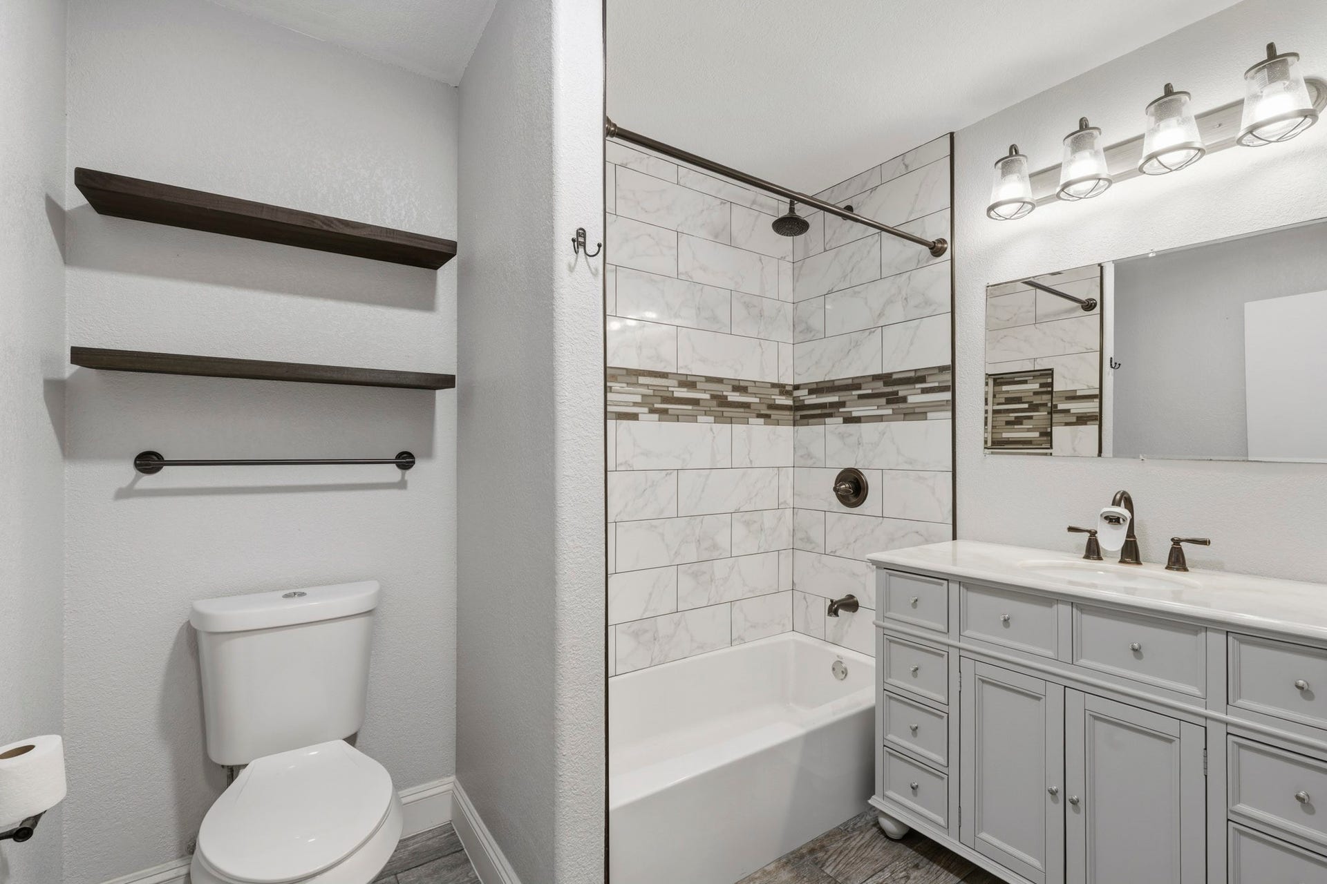 16101 Bluebird Street, Santa Fe, TX 77517 Chic and modern secondary bathroom featuring elegant tile work, a spacious vanity with sleek fixtures, complemented by open shelving for stylish storage.