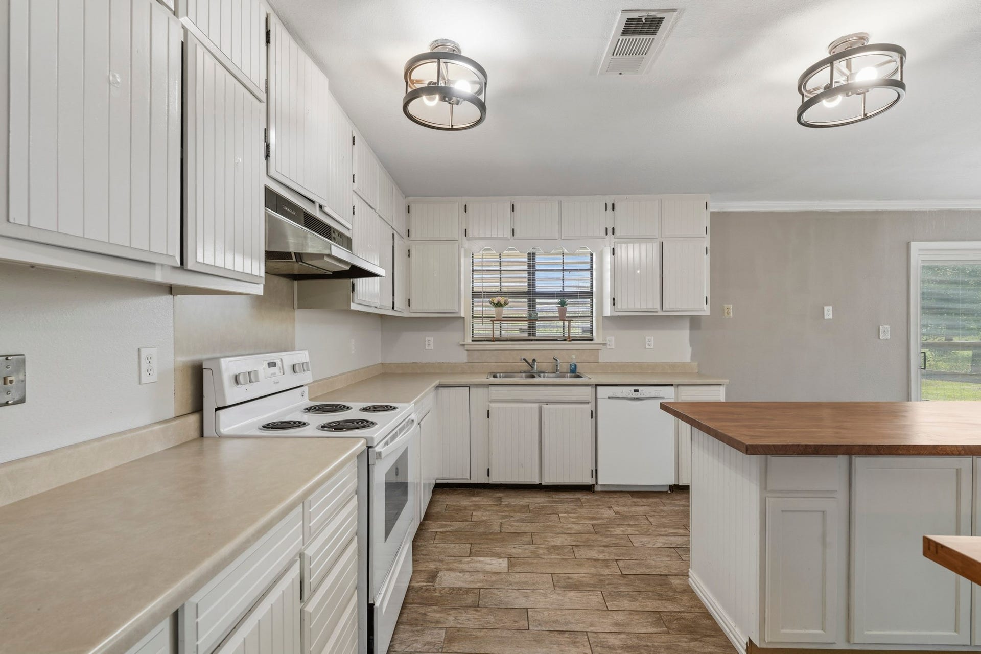 16101 Bluebird Street, Santa Fe, TX 77517 Bright and spacious kitchen with modern lighting, white cabinetry, and a central island, perfect for cooking and entertaining.