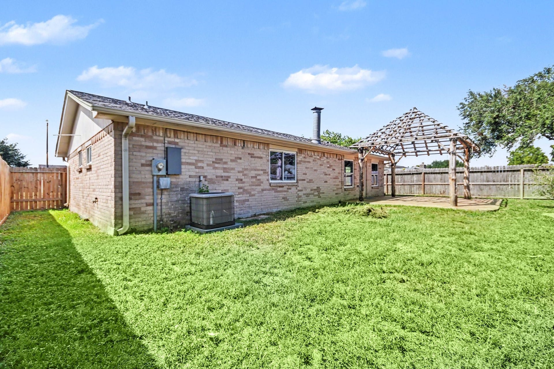 4010 Bluebonnet Trail, Deer Park, TX 77536 Charming brick home with a spacious backyard, featuring a wooden pergola perfect for outdoor gatherings.