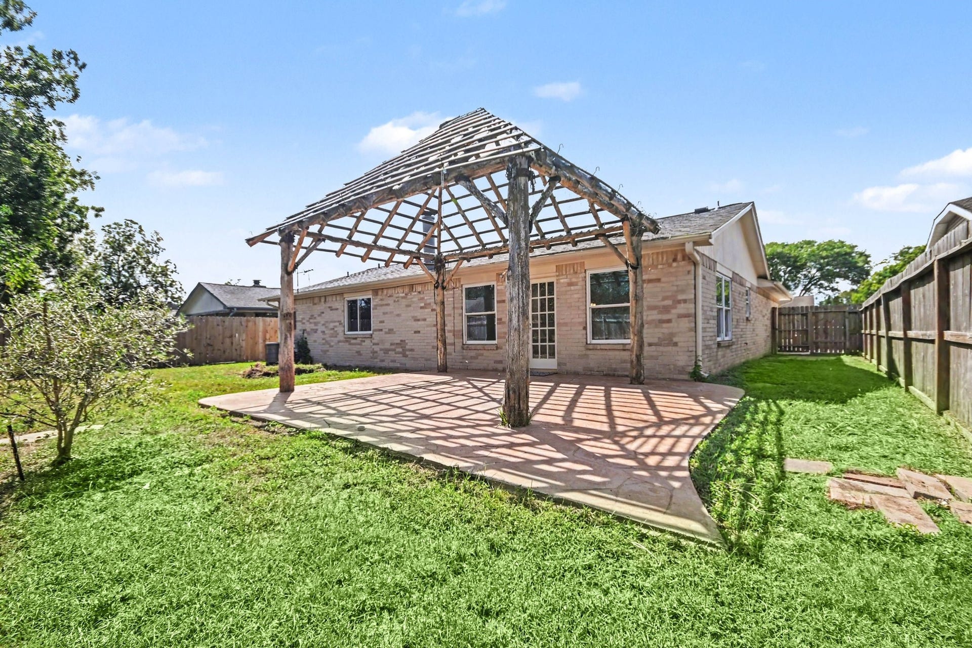 4010 Bluebonnet Trail, Deer Park, TX 77536 Charming backyard with a spacious patio and rustic wooden pergola, perfect for outdoor gatherings and relaxation.