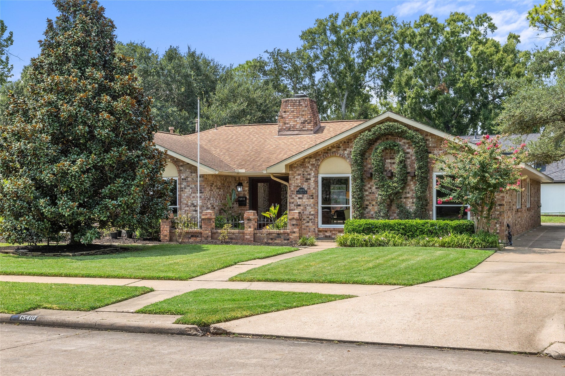 Charming brick home with lush landscaping, a welcoming front porch, and a well-maintained lawn, in Clear Lake City.