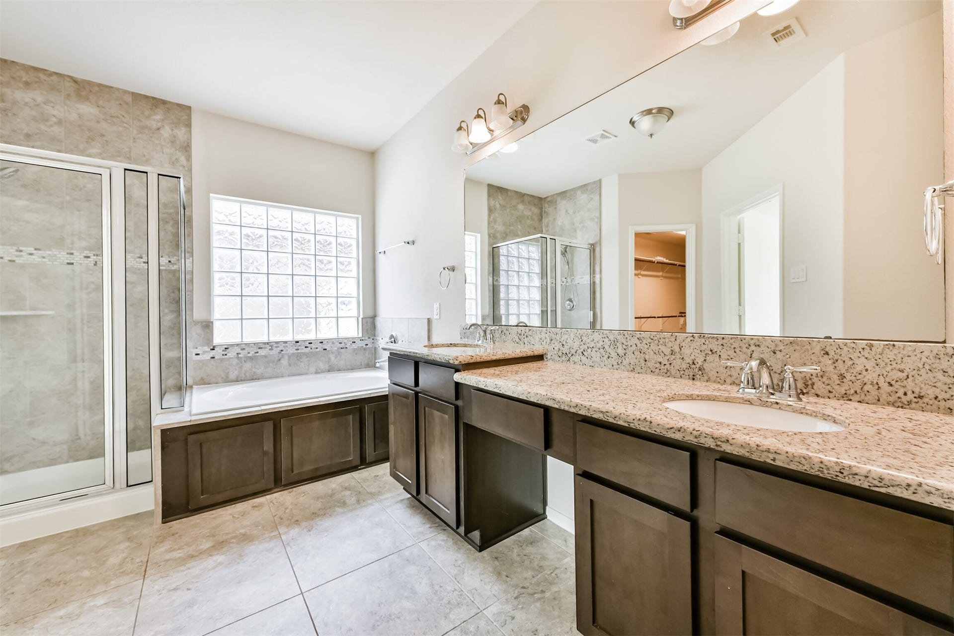 2811 Afton Drive, Pearland, TX 77581 Luxurious primary bath featuring a spacious double vanity, elegant granite countertops, a relaxing soaking tub, and a modern glass-enclosed shower. Perfect for unwinding and rejuvenation.