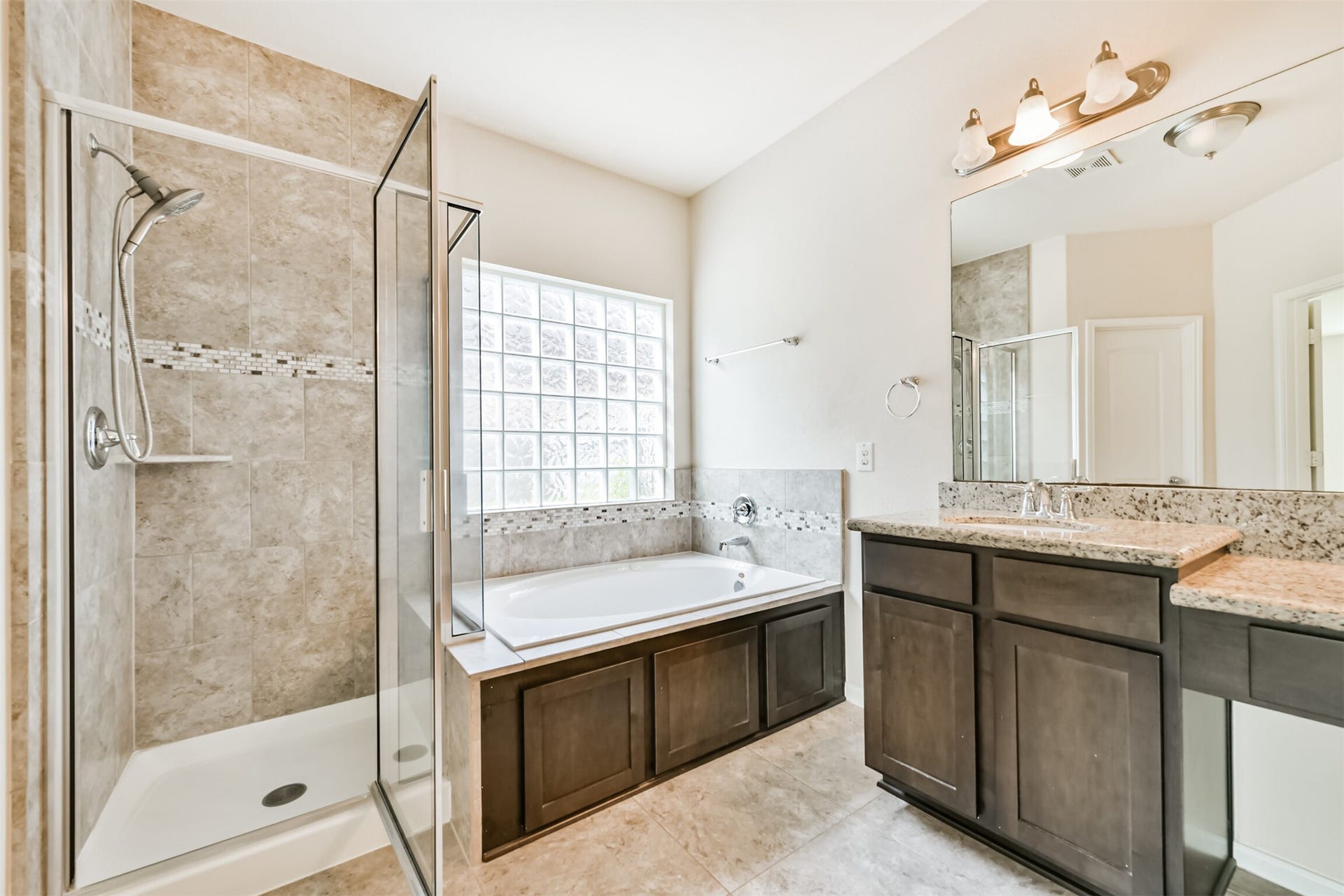 2811 Afton Drive, Pearland, TX 77581 Luxurious primary bathroom featuring a spacious glass-enclosed shower, a relaxing soaking tub, and elegant dual vanities with granite countertops. Perfect for unwinding in style.