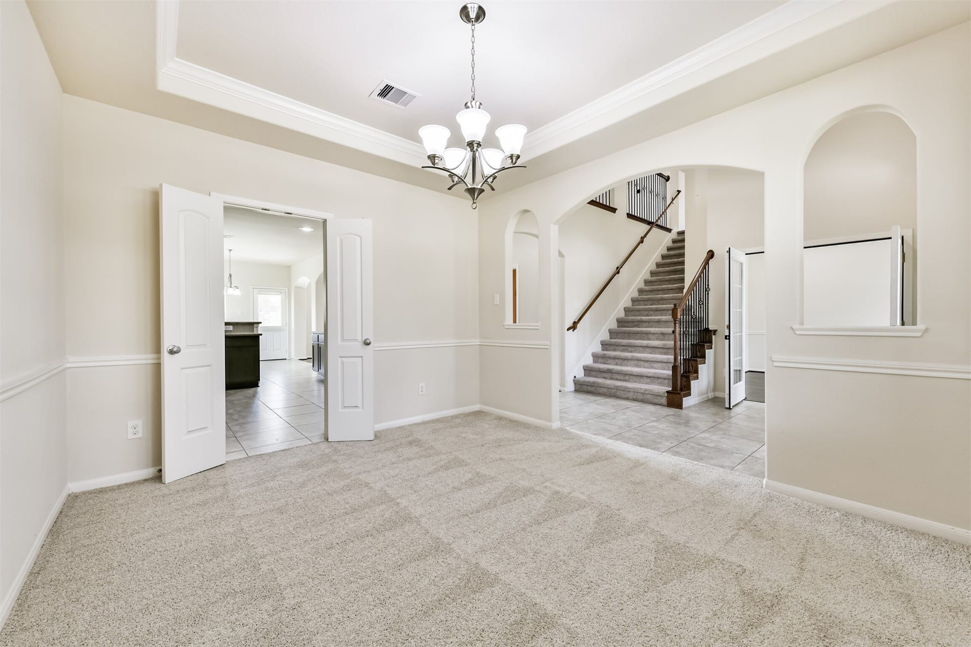 2811 Afton Drive, Pearland, TX 77581 Elegant formal dining room featuring soft carpeting, a stylish tray ceiling, and a chic chandelier, seamlessly connected to the kitchen for effortless entertaining.