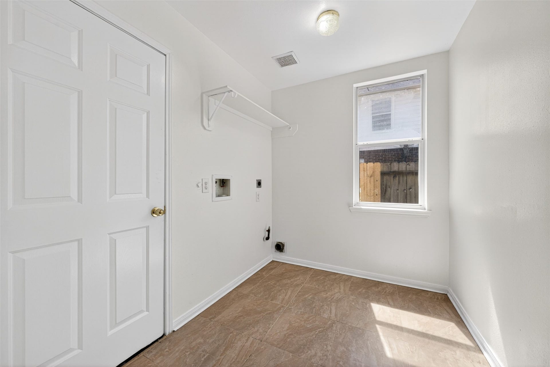 13910 Sunset View Drive, Houston, TX 77083 The laundry room provides a bright and practical space for chores, featuring durable tile flooring and a large window that keeps the area feeling fresh and airy.