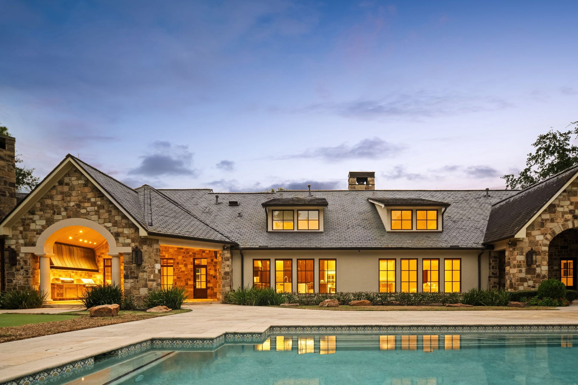 1 Gage Court, Houston, TX 77024 An evening view captures the residence, pool and outdoor living spaces illuminated across the backyard. The heated pool and separate spa sit at the center of the estates resort-style setting.